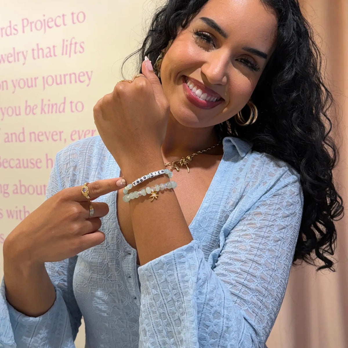 Alexia Del Valle smiling and pointing to the Todo Bien Bracelet Set on her wrist, Todo Bien bracelet and Palm Tree Charm Bracelet in mint green beads