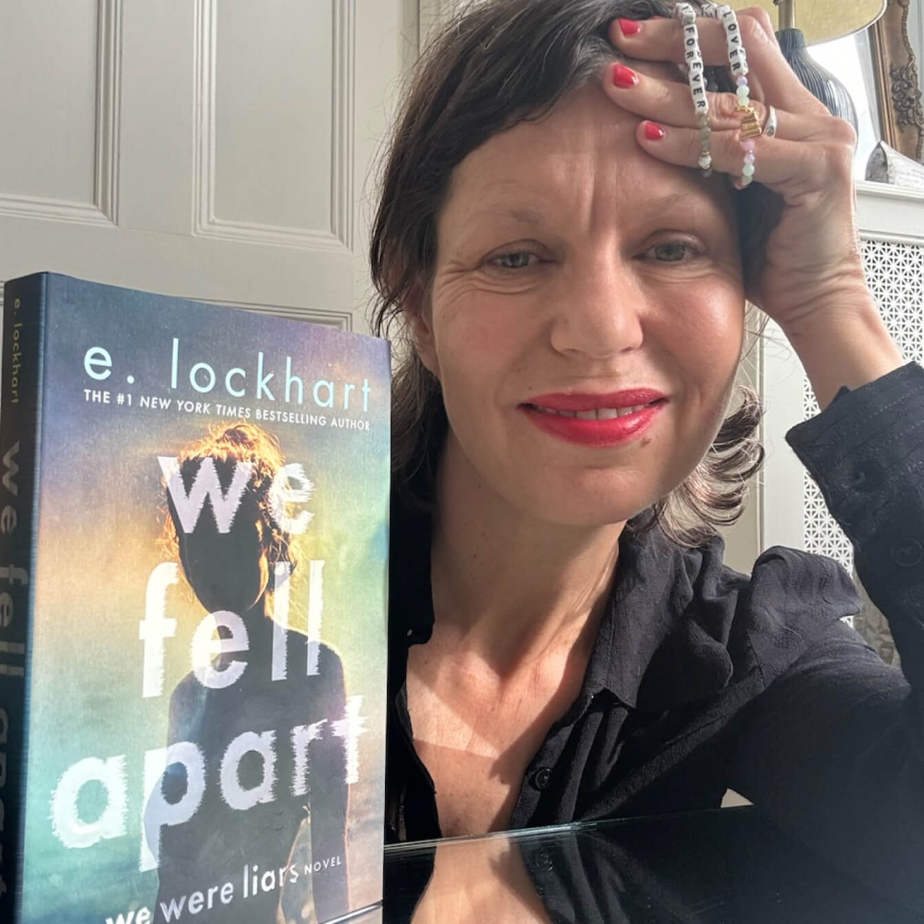Woman holding a book titled 'We Fall Apart' by e. lockhart