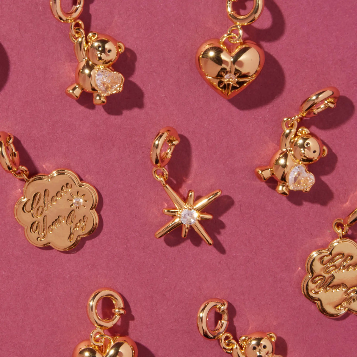 Arctic Honey Bracelet Base worn on a wrist styled with gold teddy bear gem, Choose Your Joy coin, and starburst charms, on-model on a tan background