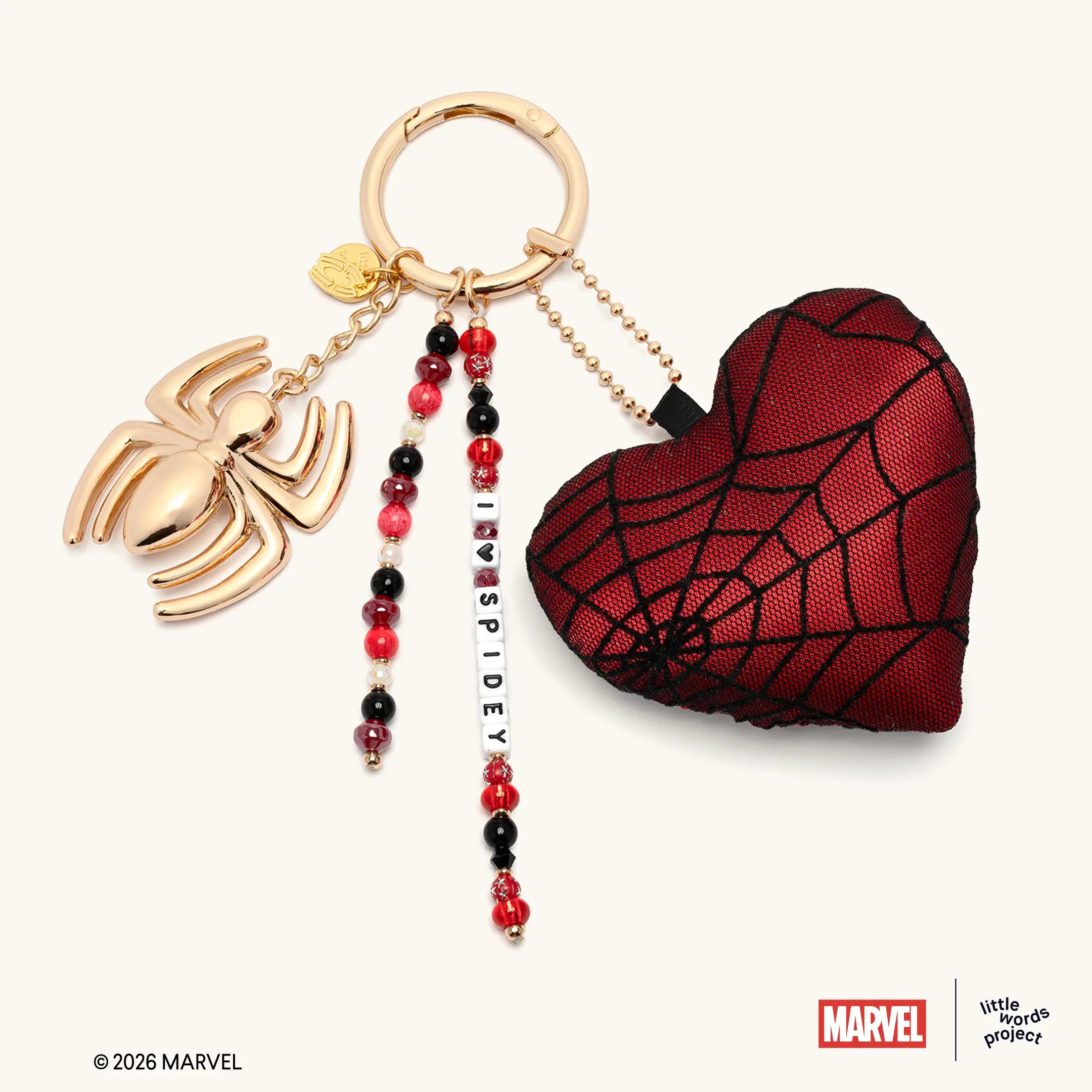I Heart Spidey Bag Charm from Marvel's Spider-Man collection, flat-lay on white background, gold spider charm with red spider-web heart plush and beaded I Heart Spidey strand on gold key ring