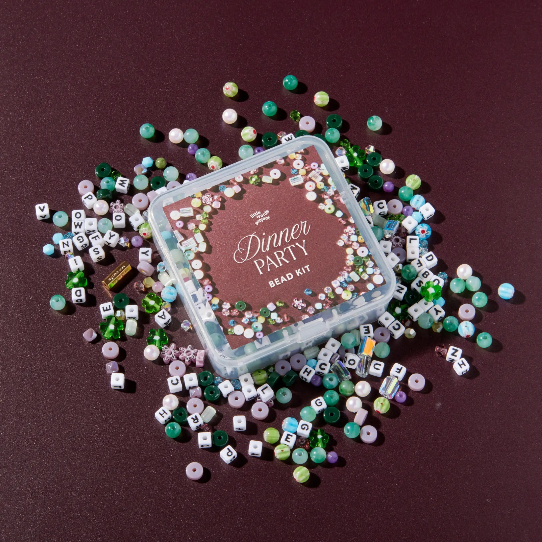 Dinner Party bead kit surrounded by multicolored beads on a dark background