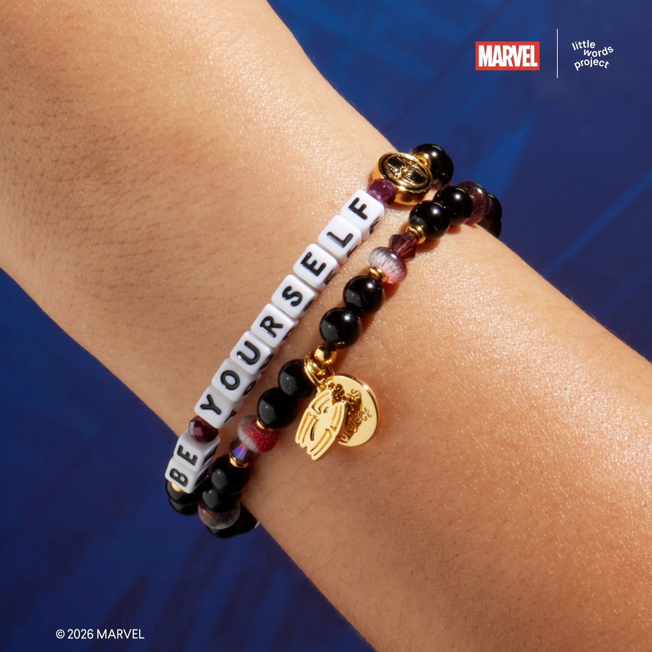 Be Yourself bracelet from Marvel's Spider-Man collection worn on wrist, on-model close-up showing black glass beads with mauve accents and gold Spider-Man casted bead