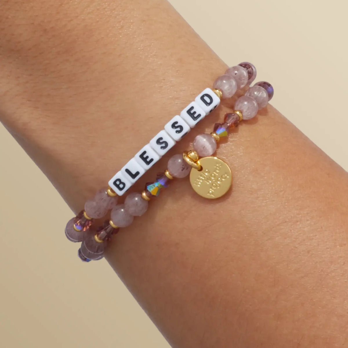 Blessed bracelet in the Holiday Spritz bead pattern with white letter beads, stacked with a second bracelet, on-model wrist shot on warm neutral background