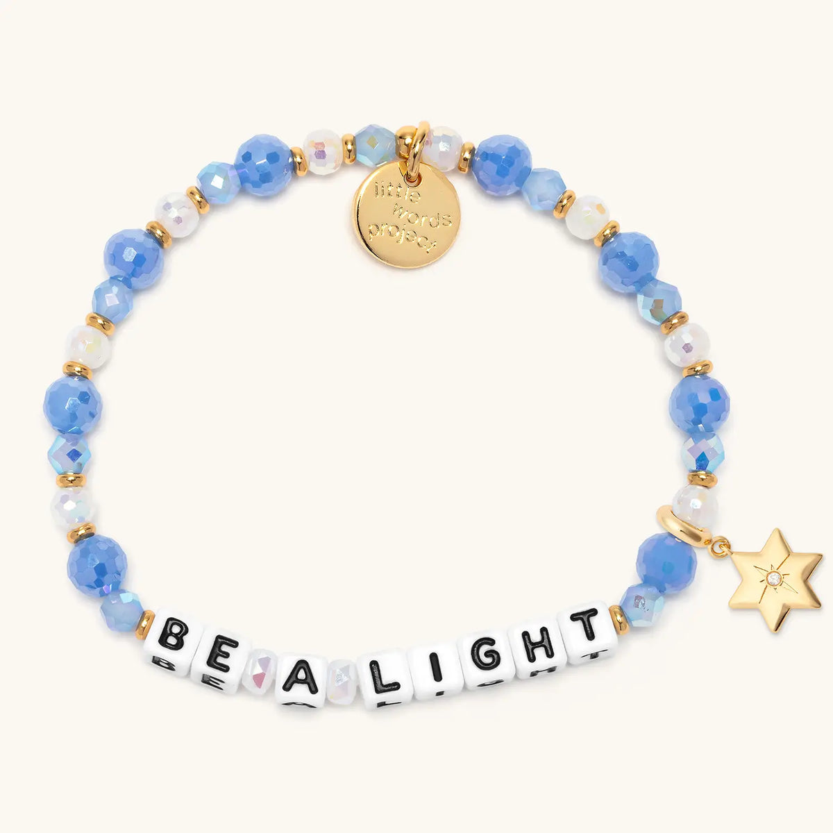 Be a Light bracelet in the Blizzard Baby bead pattern with white letter beads, gold puffy Star of David charm with a clear CZ stone, flat-lay on cream background