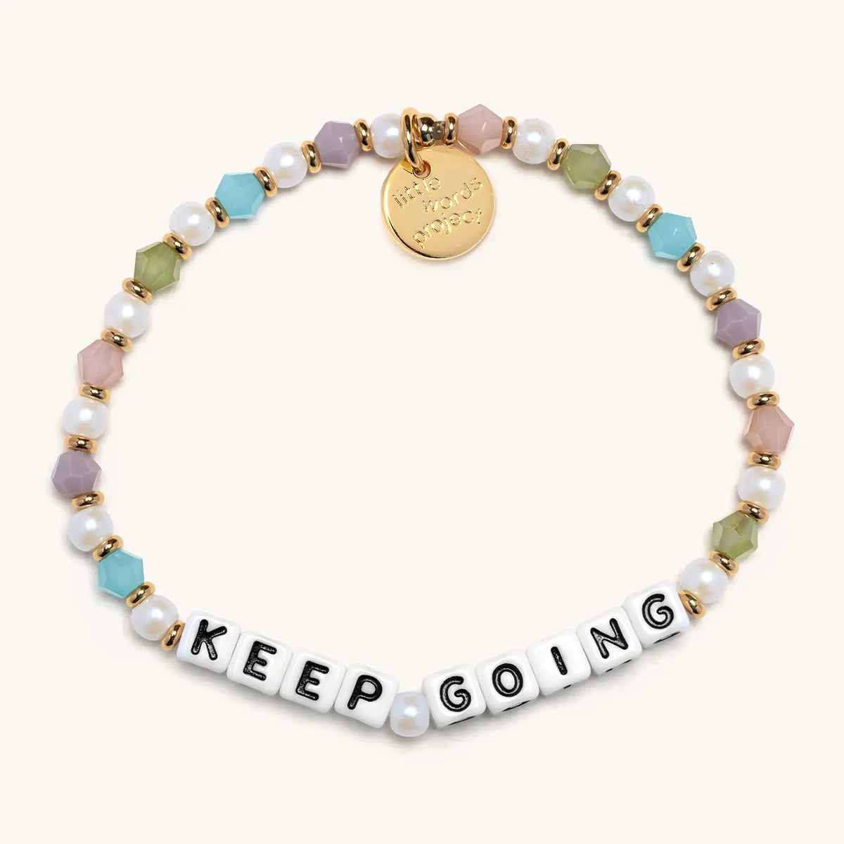 Keep Going bracelet with white letter beads from the Good Things Ahead Bracelet Set, flat-lay on cream background