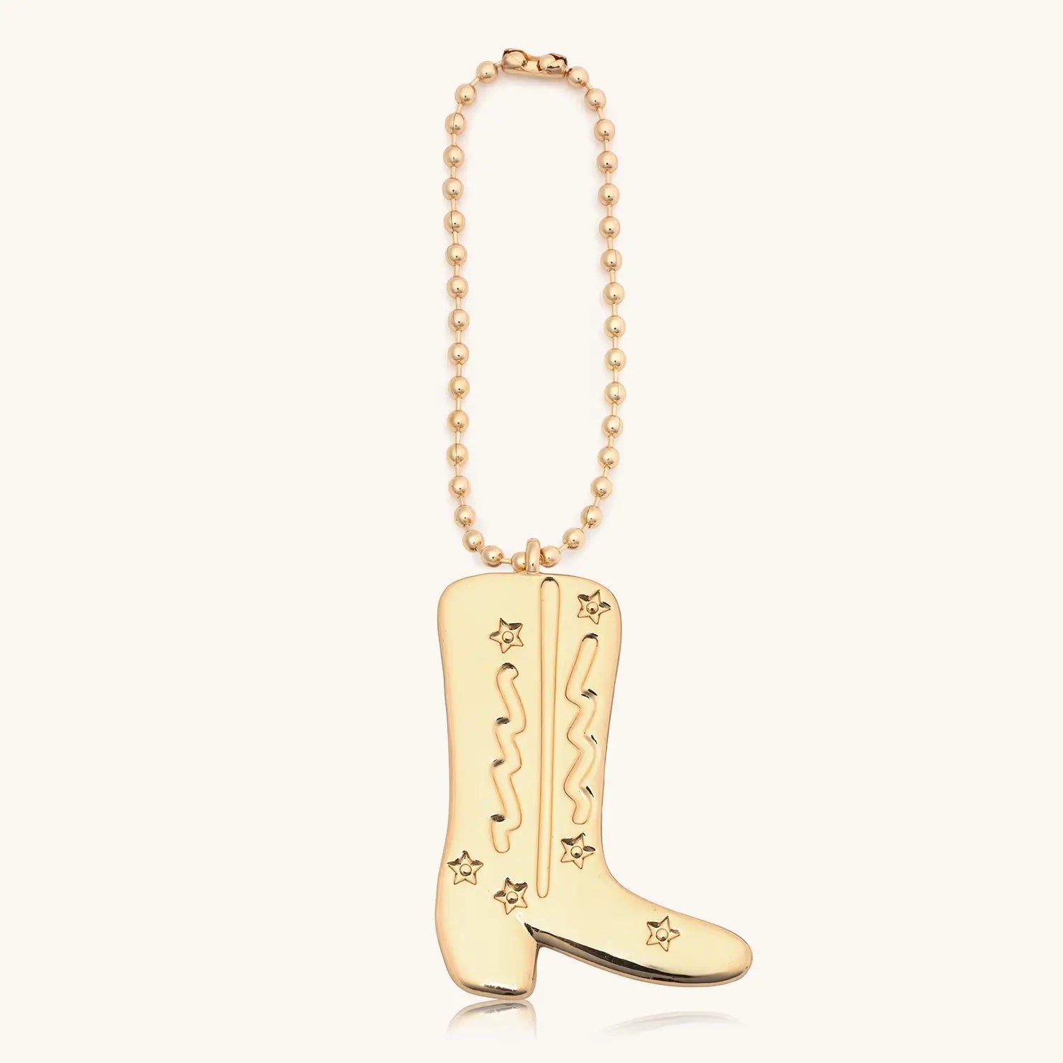 Gold cowboy boot on a bag chain against a white background
