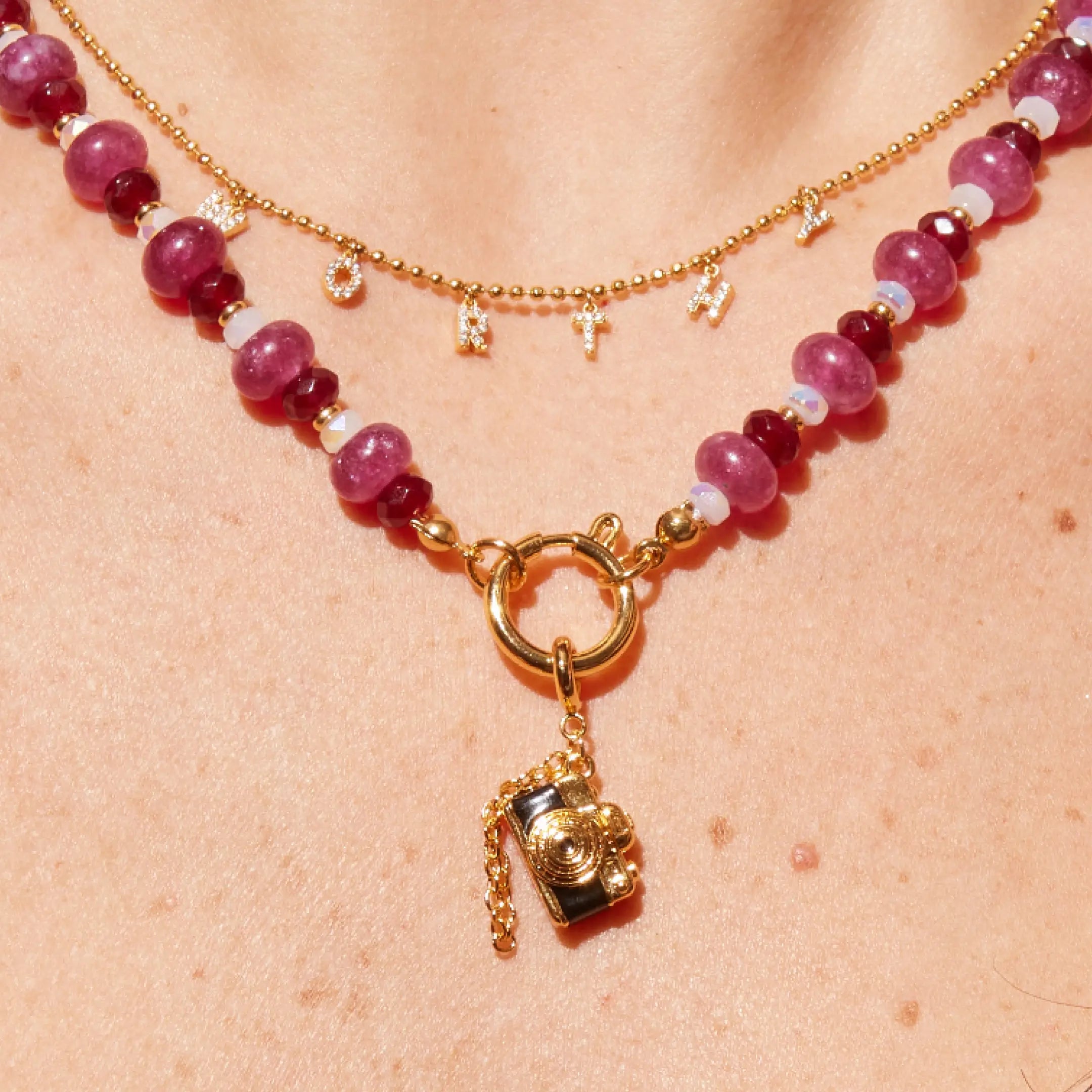 Necklace with pink beads and a gold charm on a person's neck