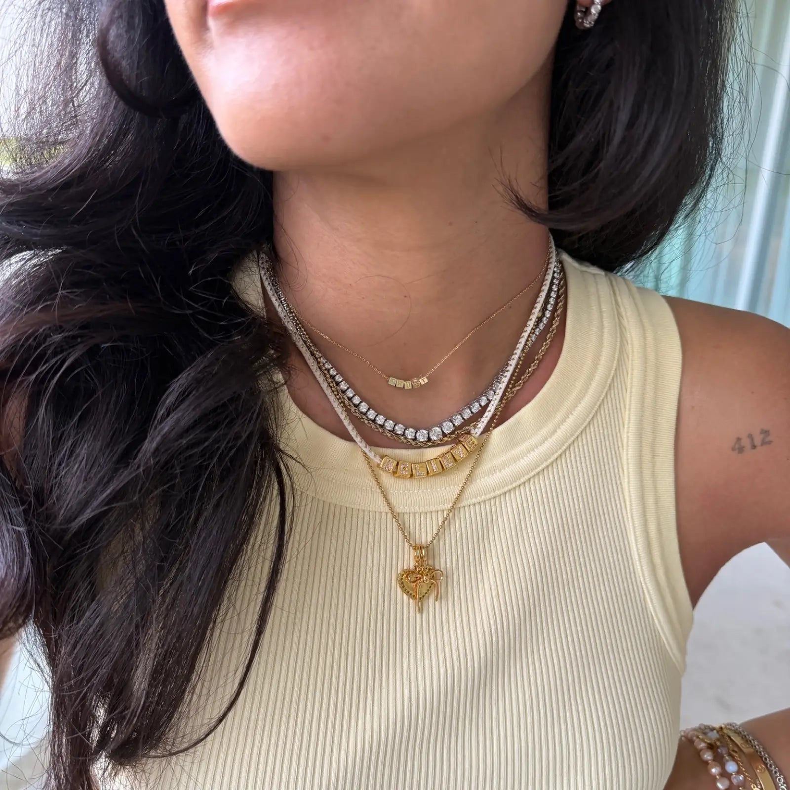 Close-up of a person wearing multiple necklaces with a neutral background