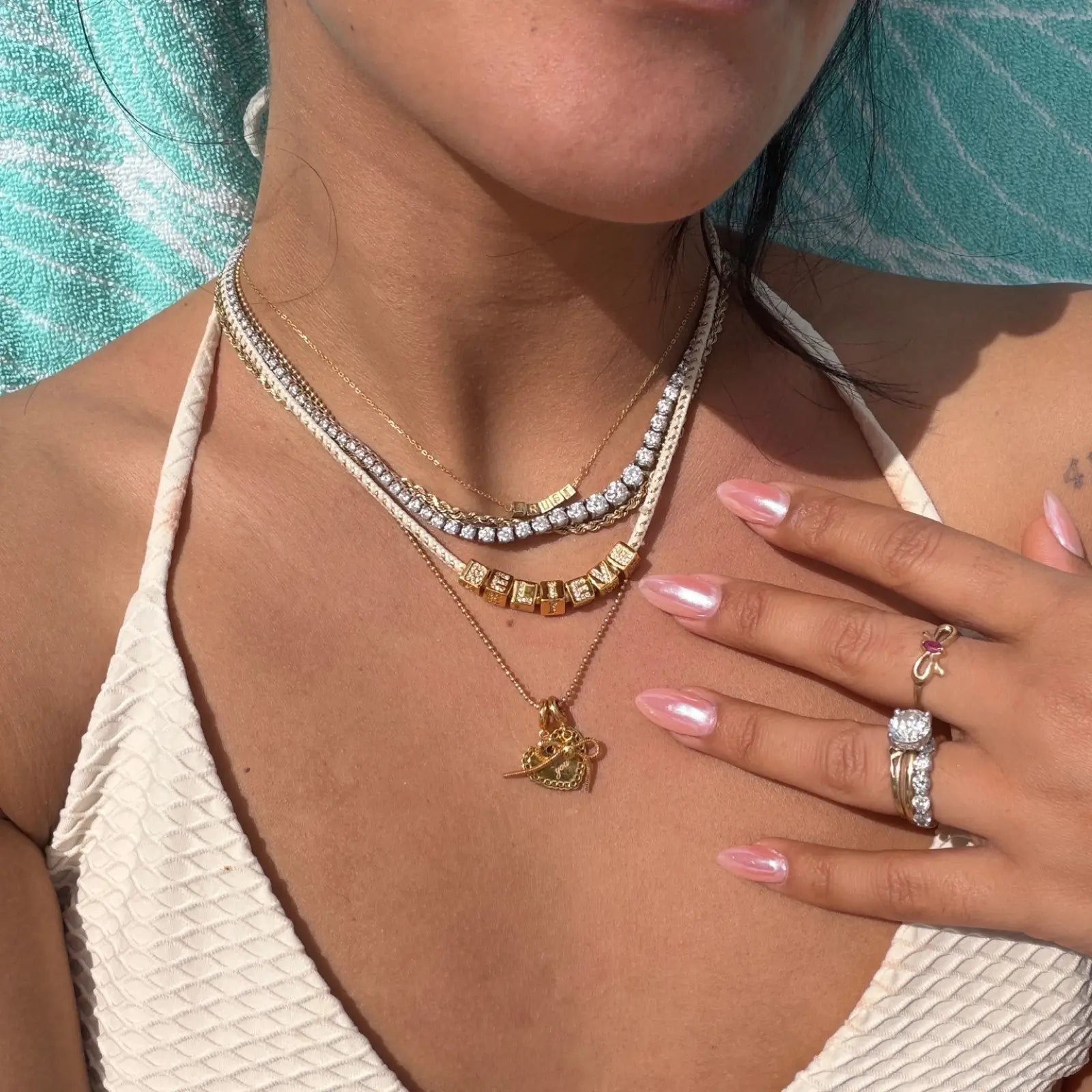 Close-up of a person wearing multiple necklaces and rings