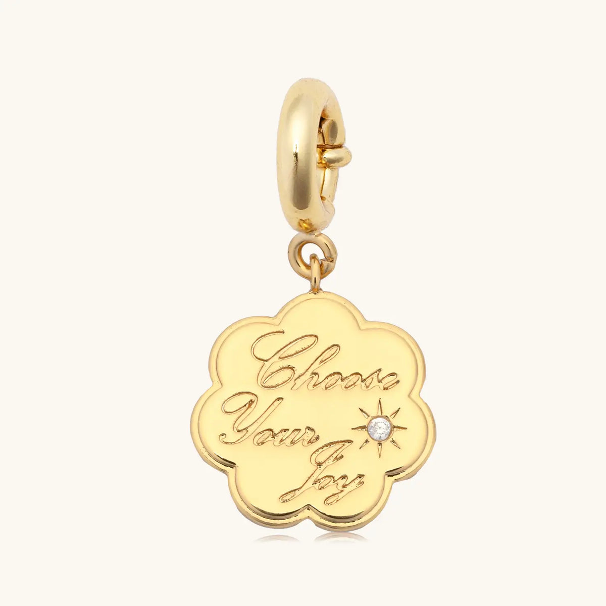Choose Your Joy Charm, gold scalloped coin charm engraved with Choose Your Joy in script with a cz accent, on a gold spring ring clasp, flat-lay on cream background