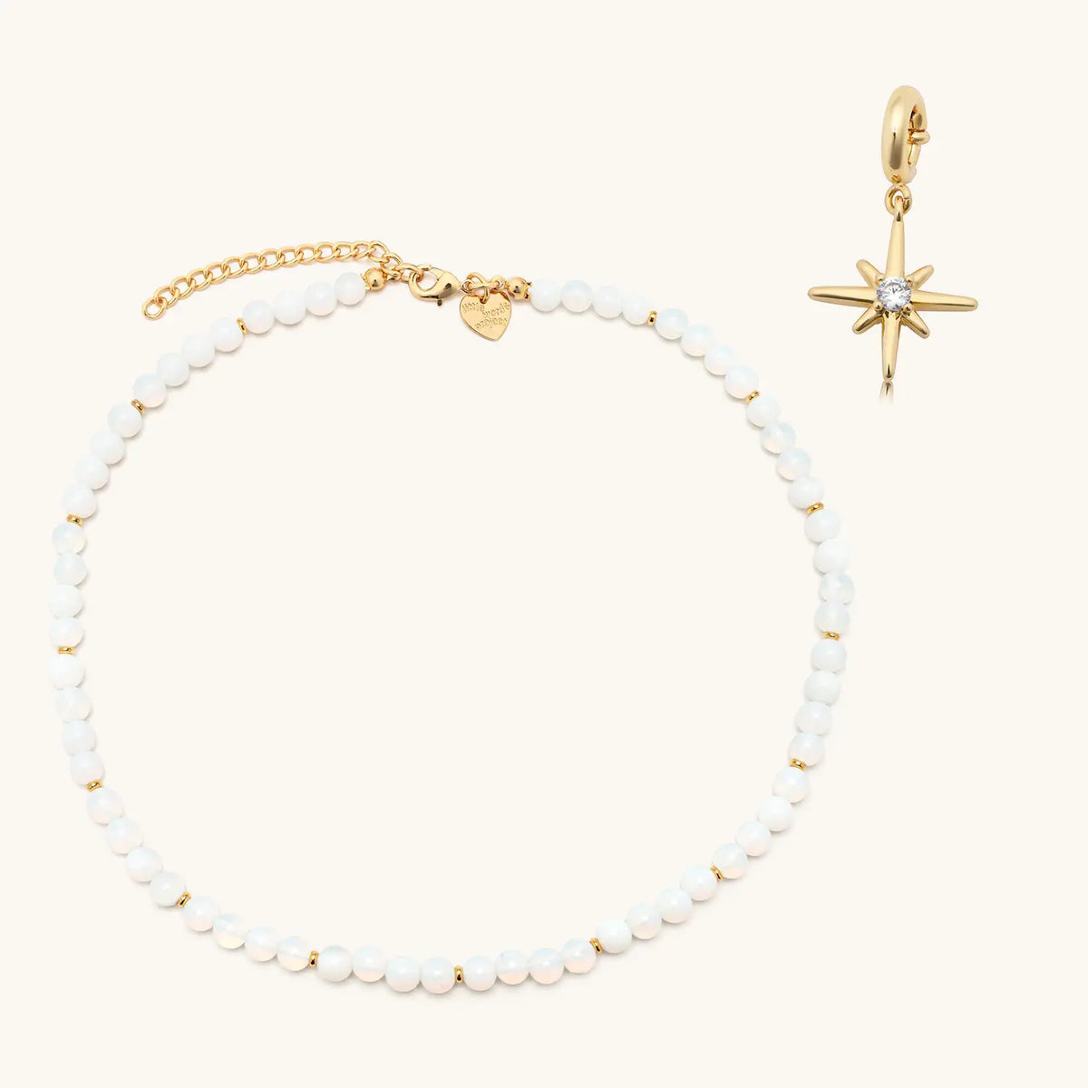 Opal Light Charm Necklace set, glowing white beaded Opal Light necklace with a gold starburst charm shown beside it, flat-lay on cream background