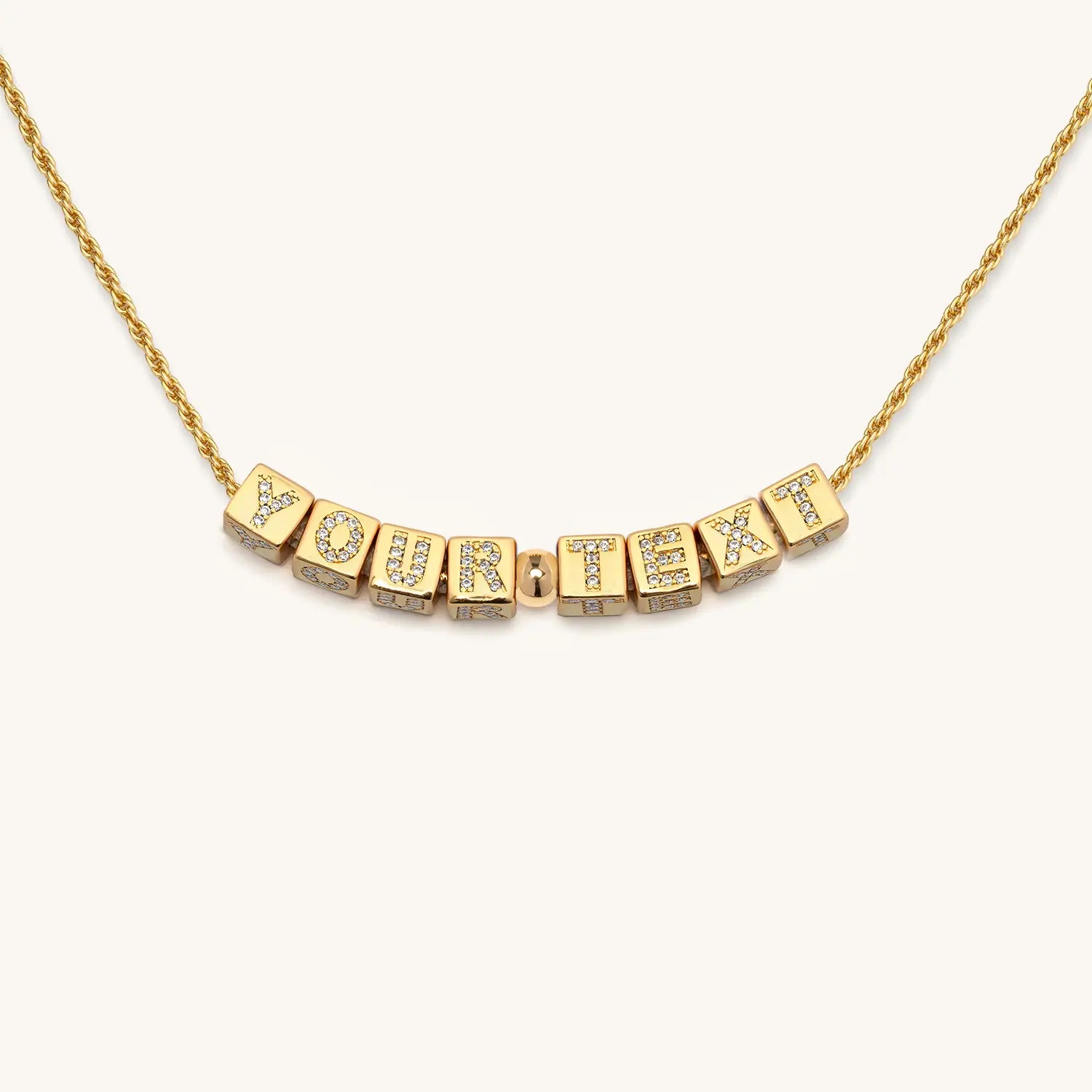 Gold necklace with CZ-studded letters on a white background