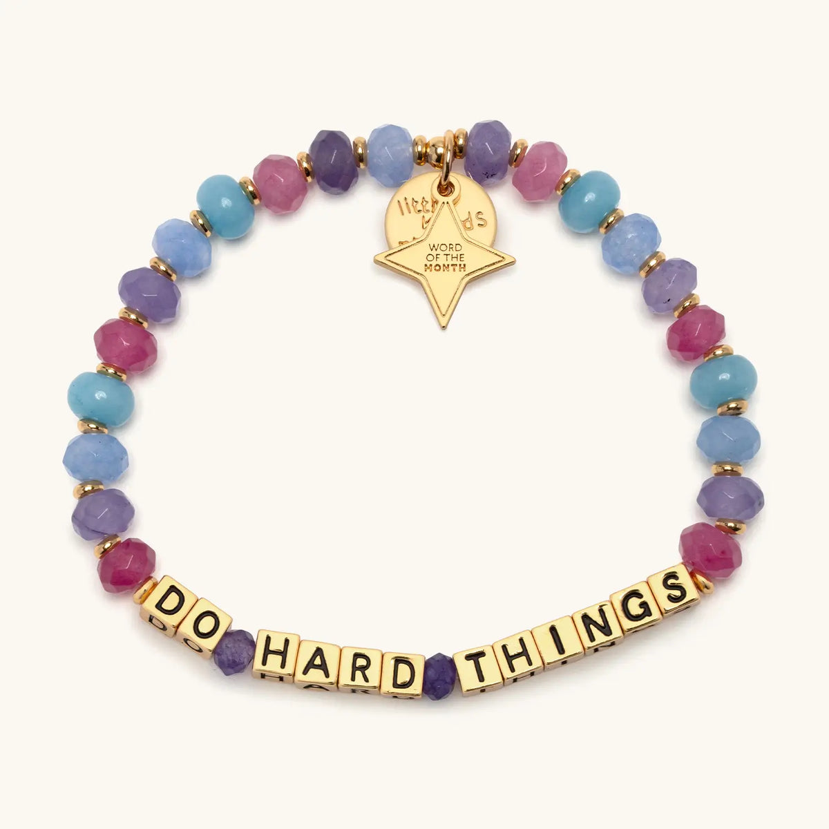 Do Hard Things September Word of the Month bracelet with gold letter beads, pink, purple, blue and teal faceted beads, gold spacers and a gold star Word of the Month charm, shown flat on a cream background