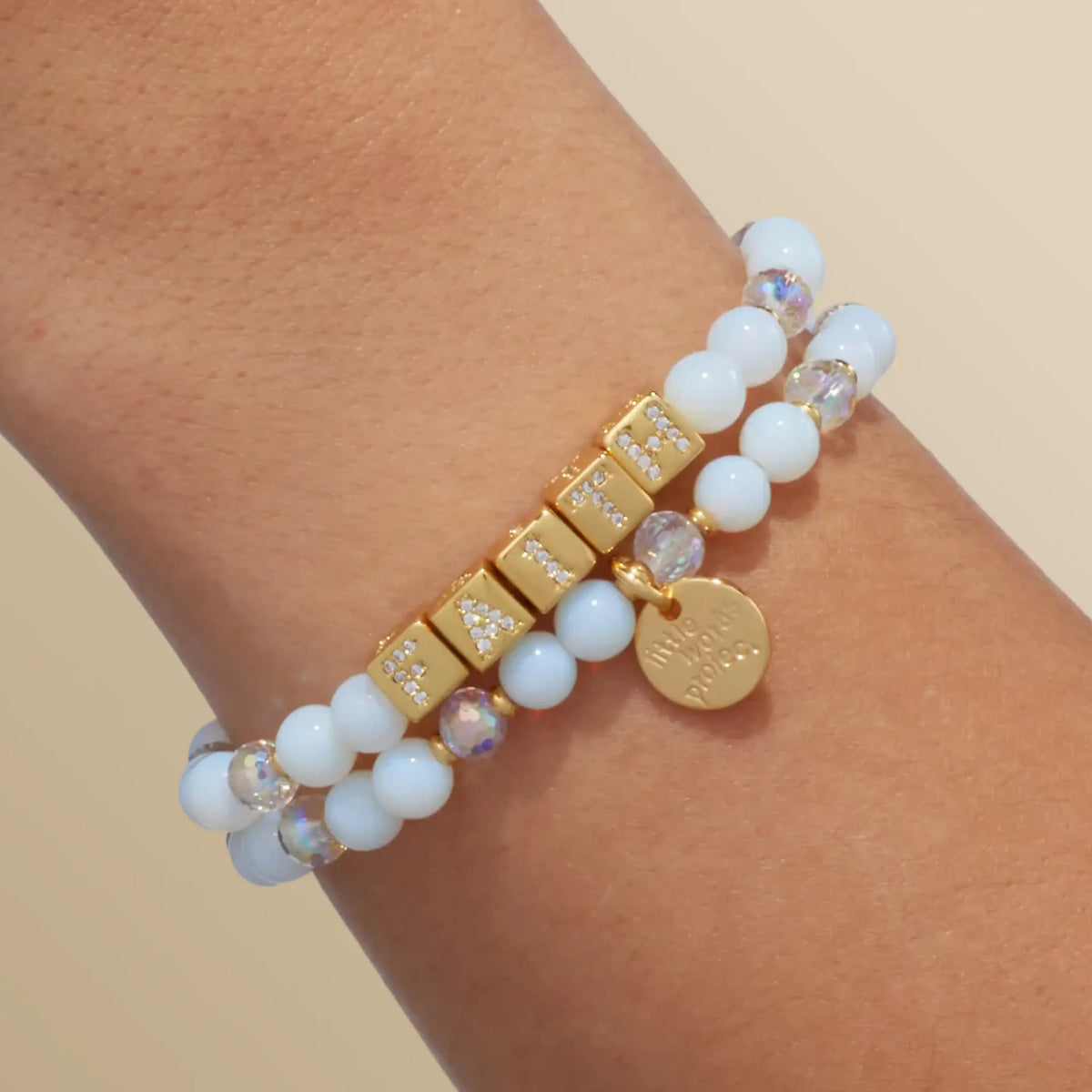 BOLDER Faith Bracelet in the Icicle Energy bead pattern with gold CZ letter blocks, stacked with a second bracelet, on-model wrist shot on warm neutral background