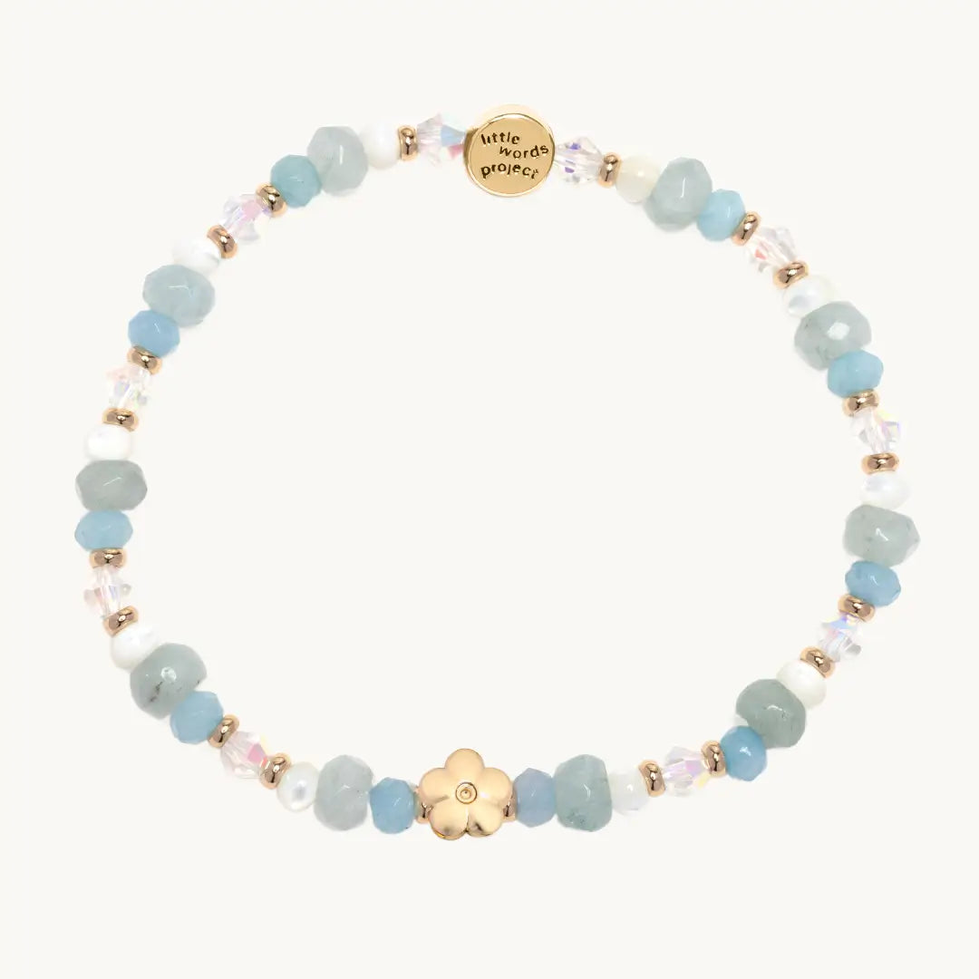 Bracelet with pastel beads and gold flower on a white background