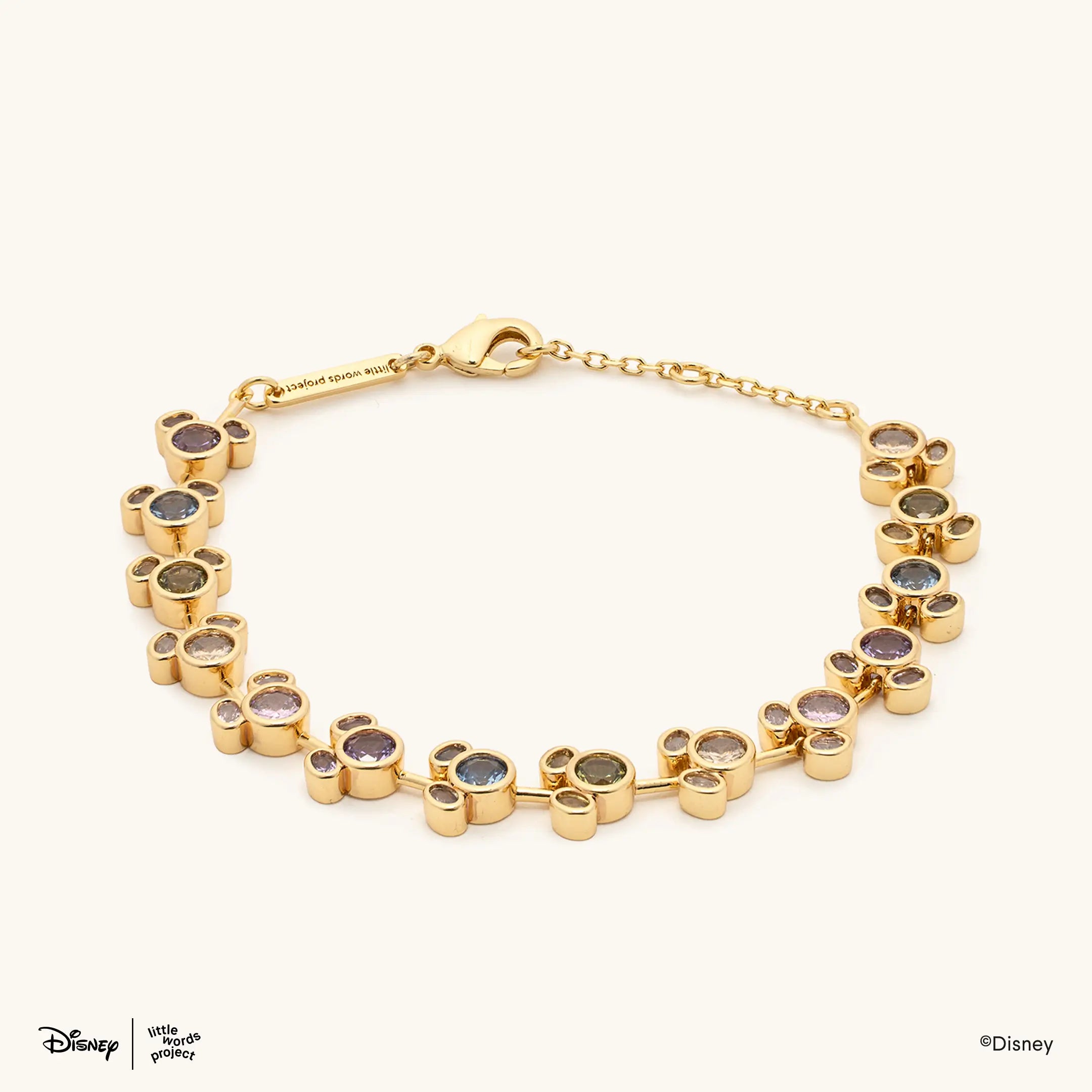 Mickey Mouse Rainbow Bracelet from Disney Mickey and Friends laid flat on cream, full gold plated chain with clasp and multicolor crystal Mickey Mouse links
