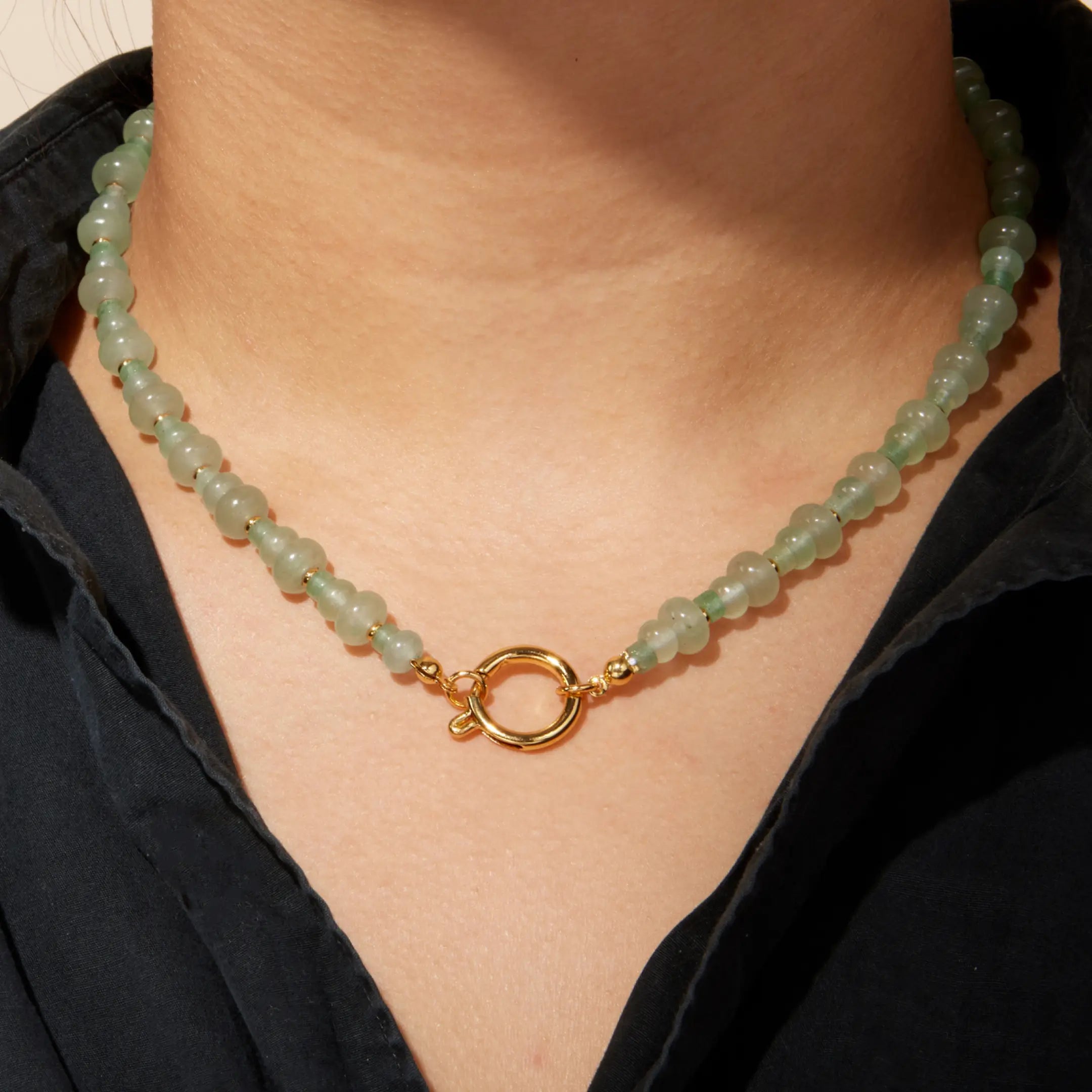 Necklace with green beads and gold clasp worn by a person