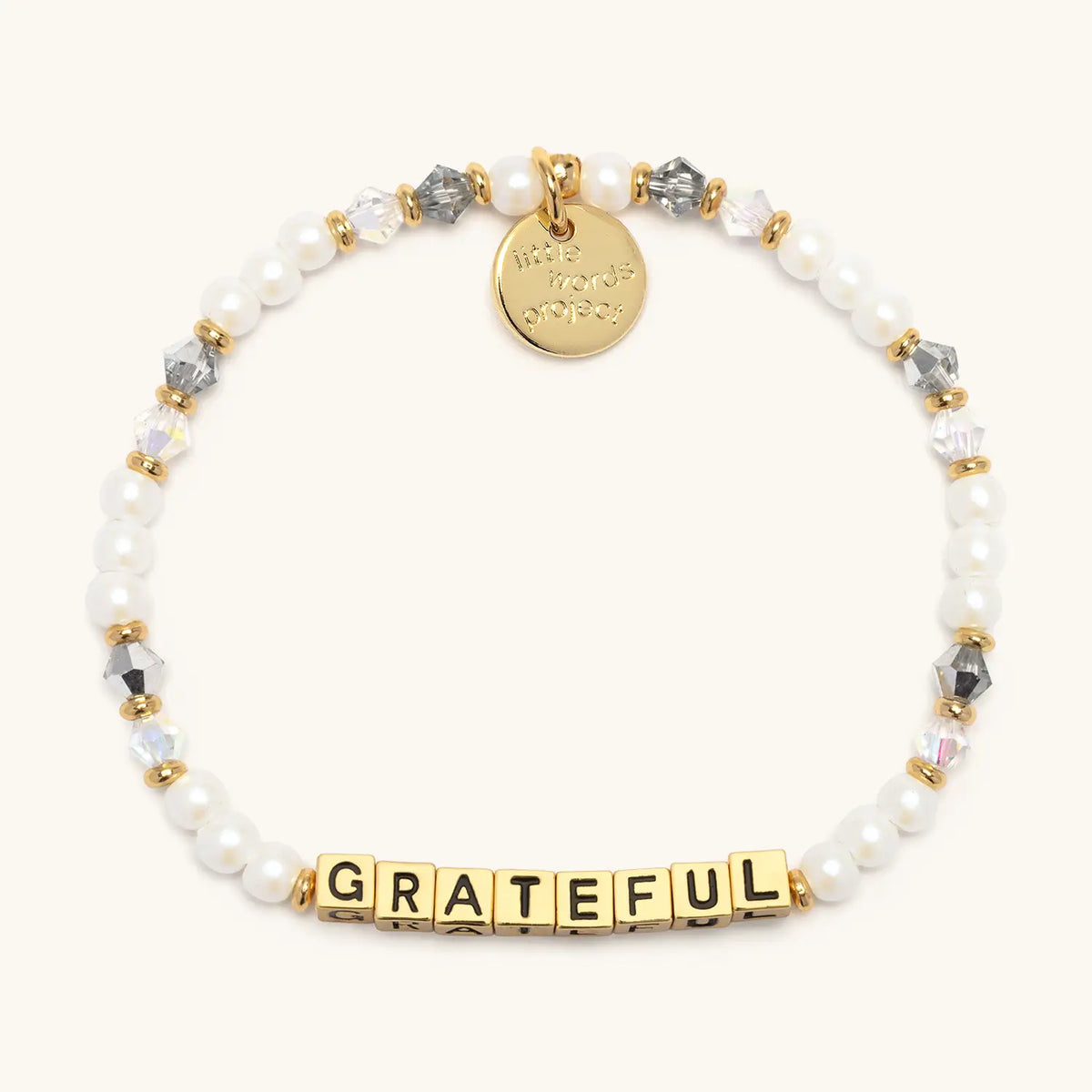 Grateful bracelet with gold letter beads from the Little Reminders Bracelet Set, flat-lay on cream background