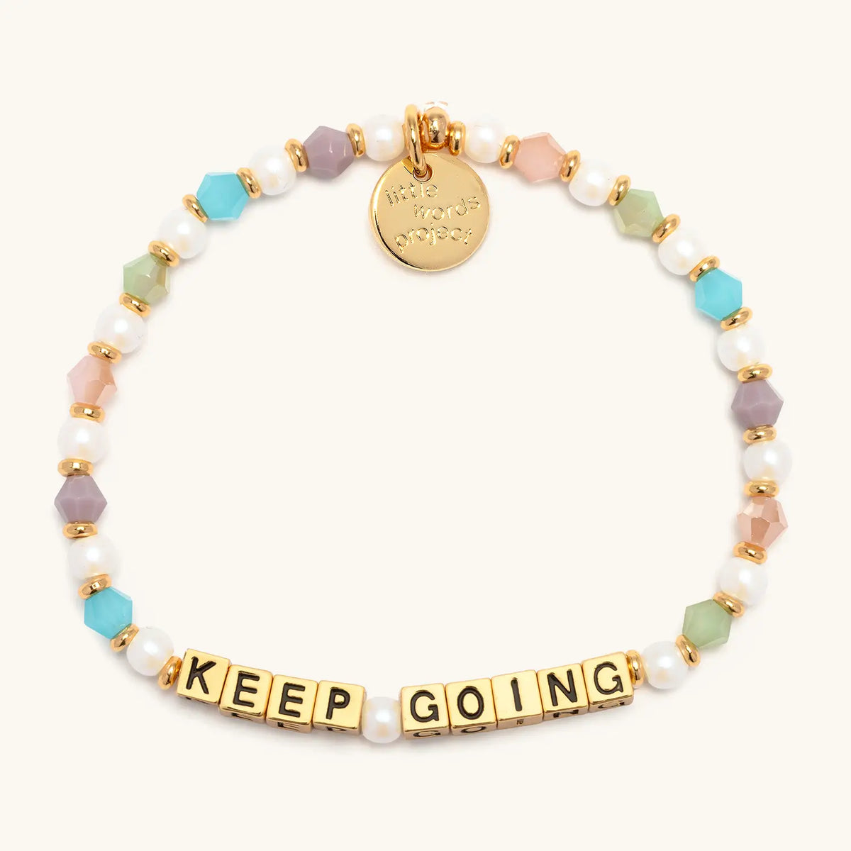 Keep Going bracelet with gold letter beads from the Good Things Ahead Bracelet Set, flat-lay on cream background