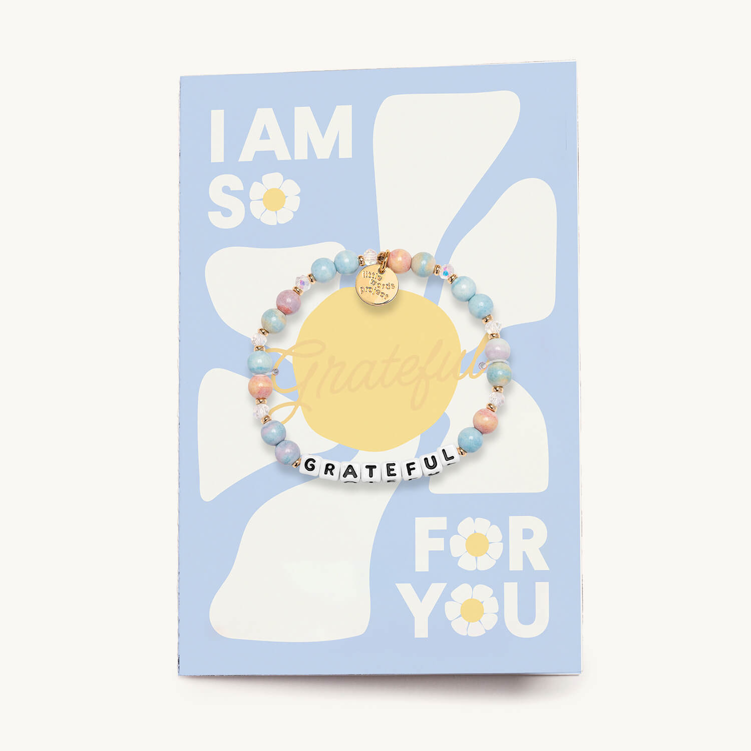 A bracelet with multicolored beads with the word 'grateful' written on it, presented on a blue card with the text 'I AM SO GRATEFUL FOR YOU'.
