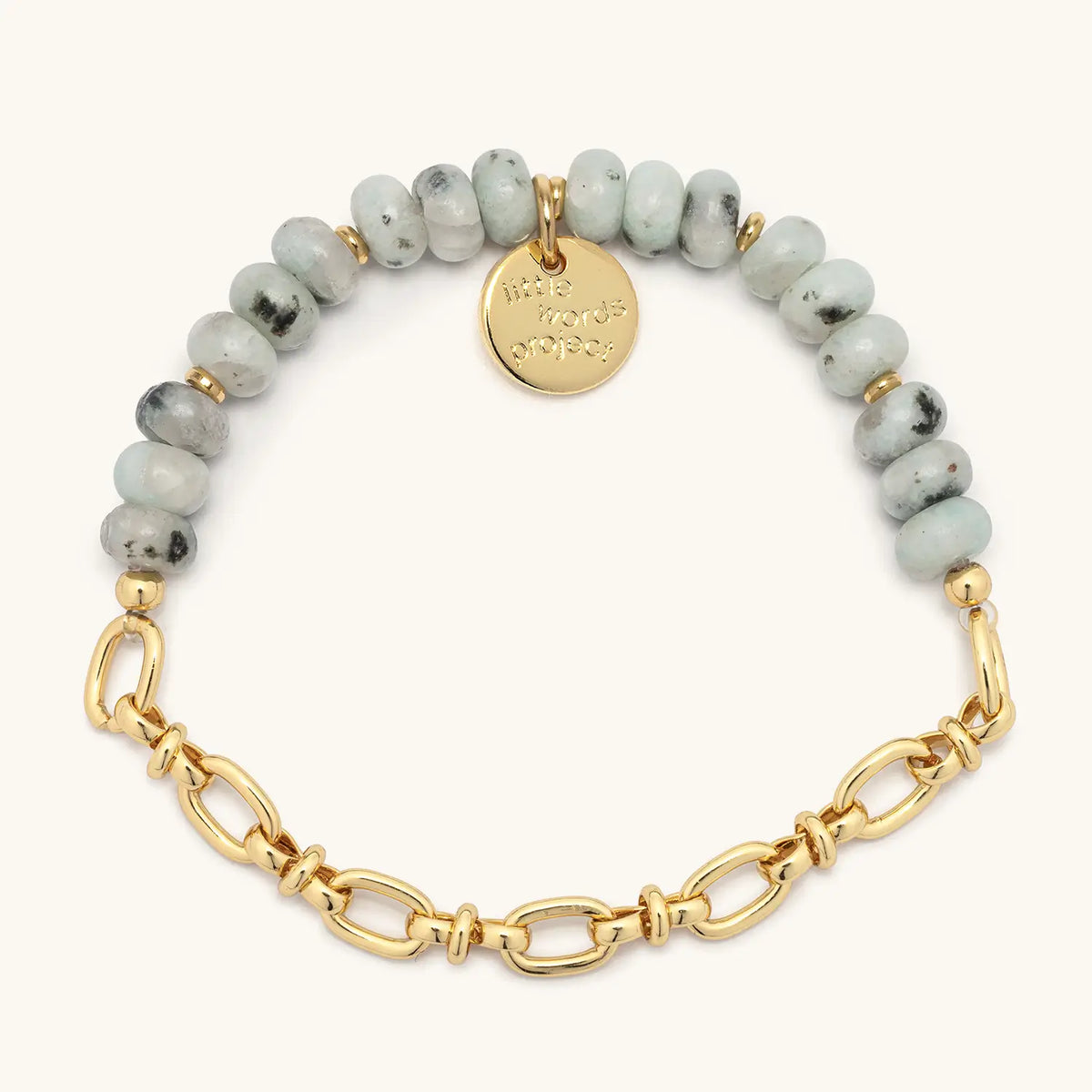 Smoky Ink Bracelet Base, half beaded and half chain, speckled mint green semi-precious stone beads with a gold link chain and gold logo coin tag, flat-lay on cream background
