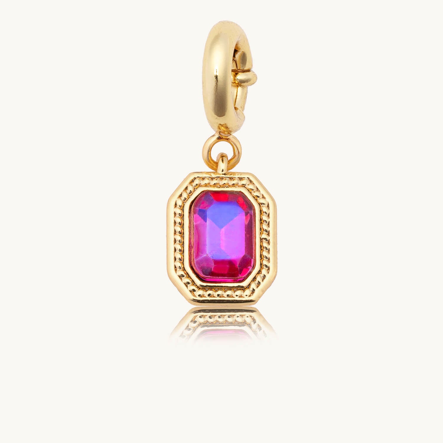 Gold charm with a pink gemstone on a white background