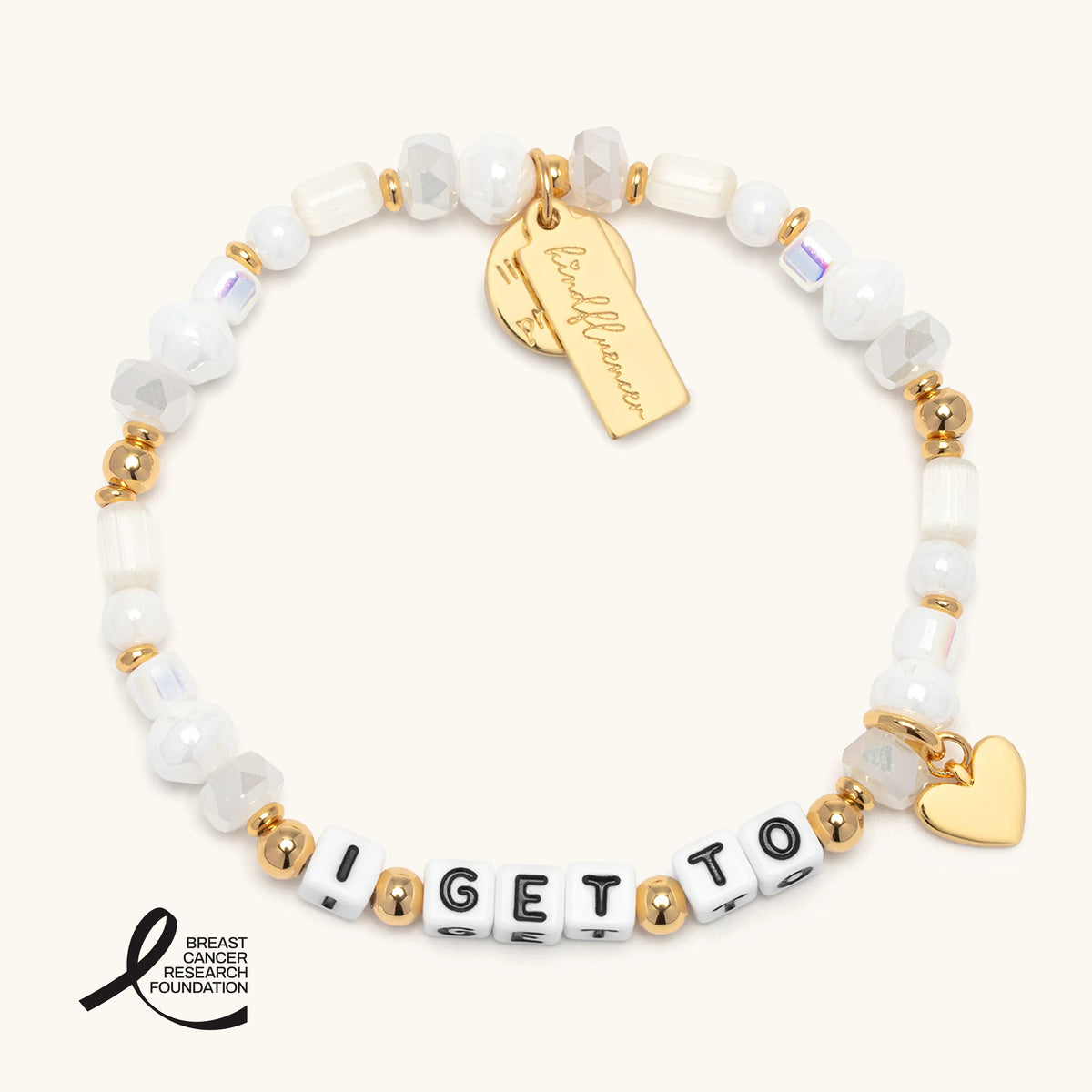 I Get To Charm Bracelet in the Ivory Sparkle bead pattern, white letter beads with white faux pearls, iridescent crystals, and frosted glass beads with gold accents, a gold heart charm and gold Kindfluencer tag, flat-lay on cream background with the Breast Cancer Research Foundation logo