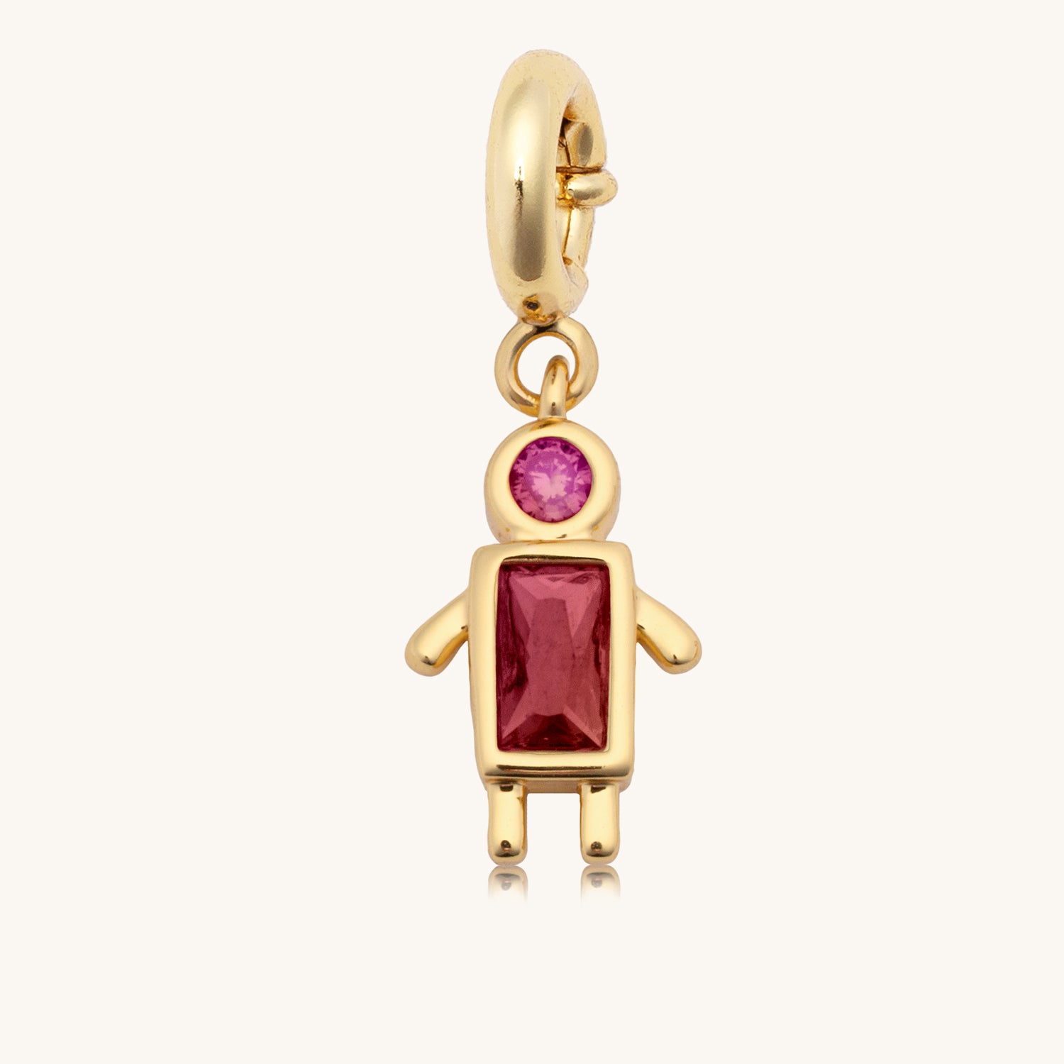 Gold charm with a red gemstone on a white background