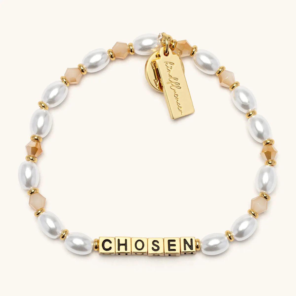 Chosen bracelet by Kirstin Czernek, gold letter beads with white faux pearls and champagne crystals with gold accents, flat-lay on cream background