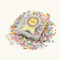 Kindness Wins Bead Kit contents flat-lay showing alphabet letter beads, smiley face beads, and assorted crystal beads in summer colors
