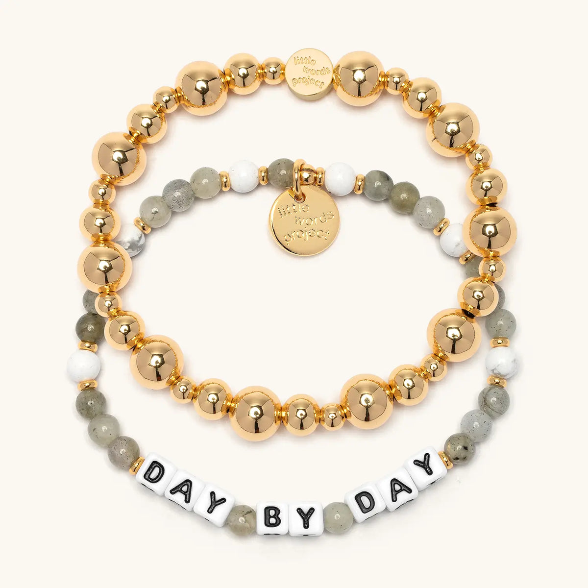 Day by Day Bracelet Set from the Project HEAL giveback collection, the gold plated Gold Bubbles bracelet base stacked above the Day by Day bracelet in grey and white semi-precious stone beads