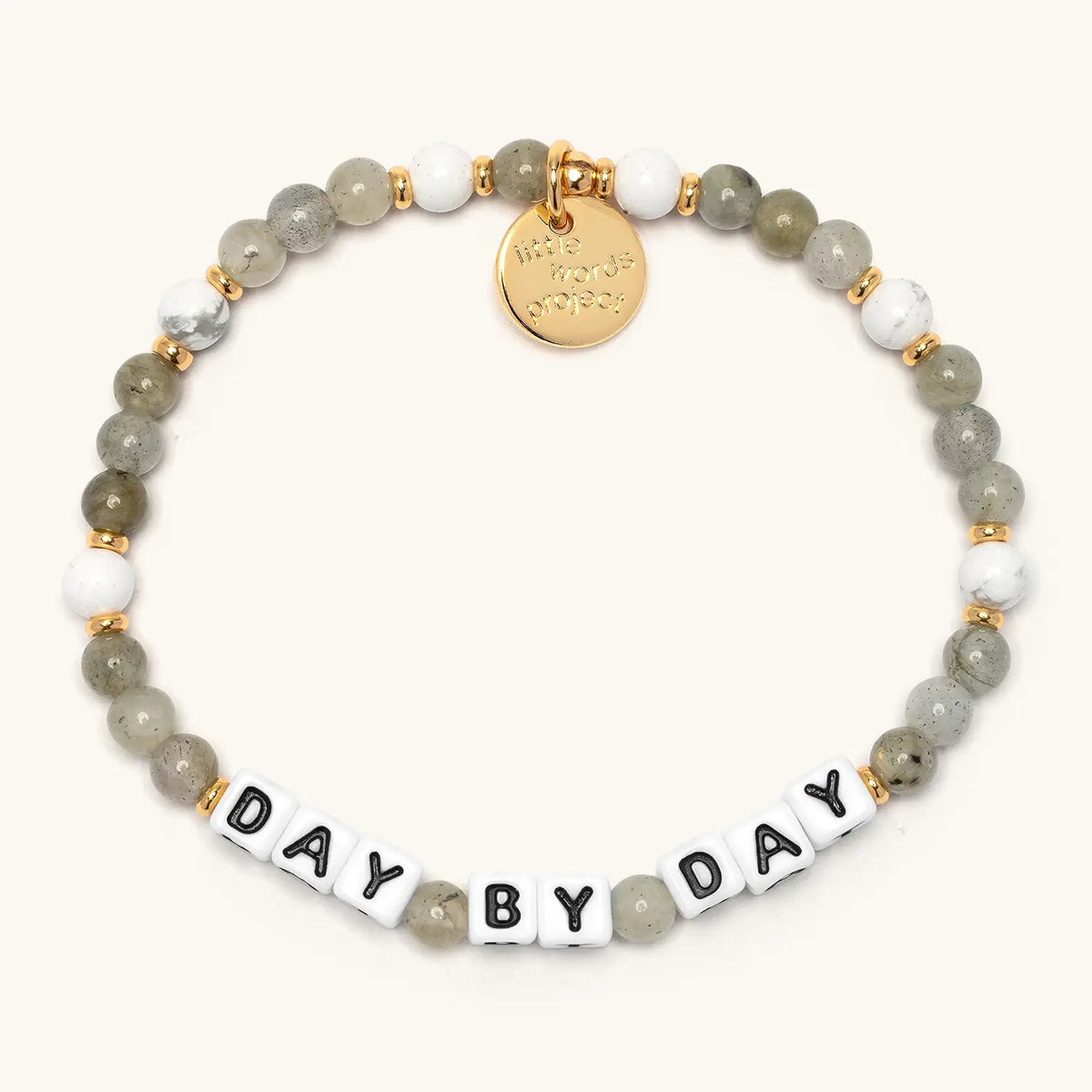 Day by Day bracelet from the Project HEAL giveback collection, grey and white semi-precious stone beads with gold accents, black and white letter beads spelling DAY BY DAY, and a gold Little Words Project logo tag