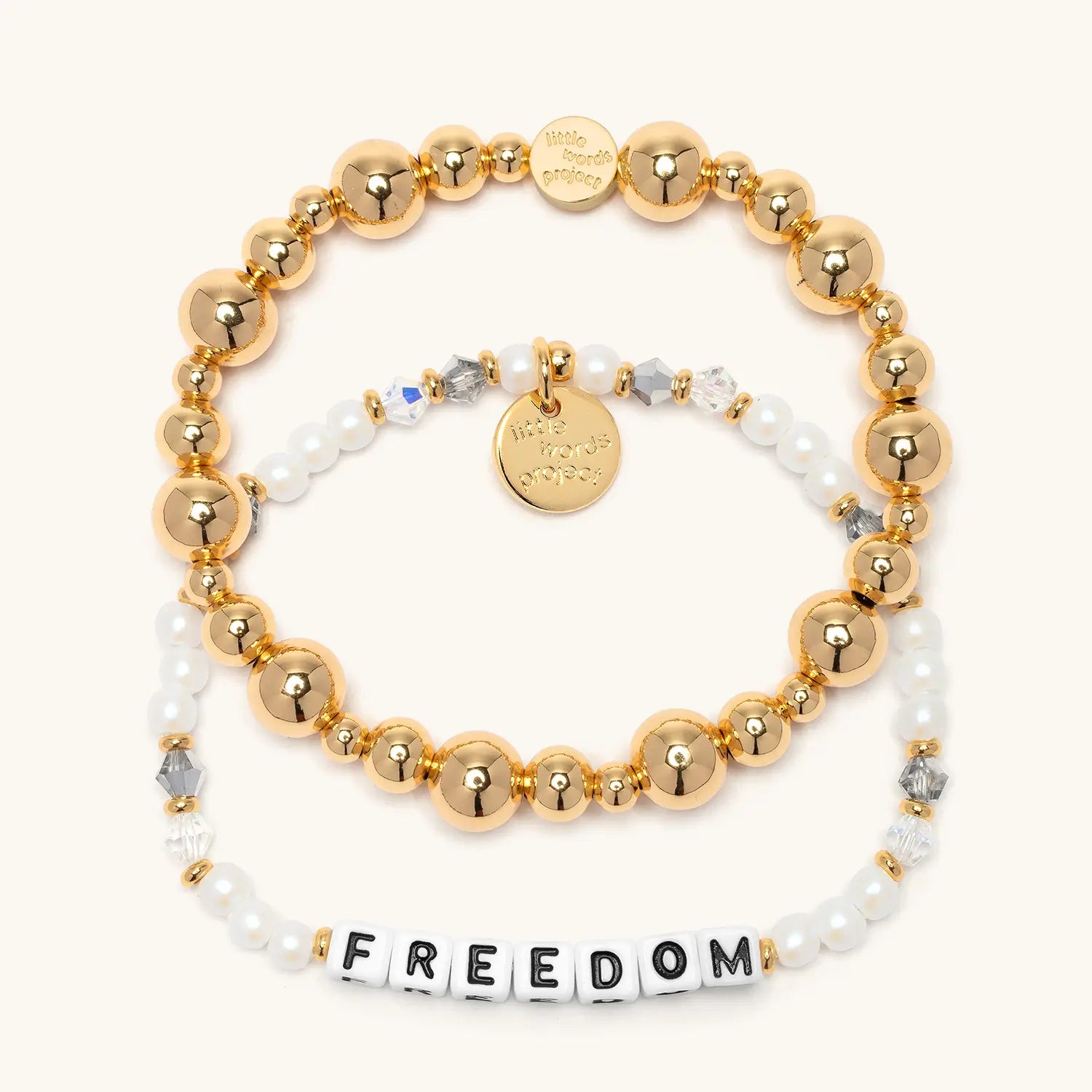Freedom Bracelet Set from the Project HEAL giveback collection, the gold plated Gold Bubbles bracelet base stacked above the Freedom bracelet in white faux pearl and crystal beads