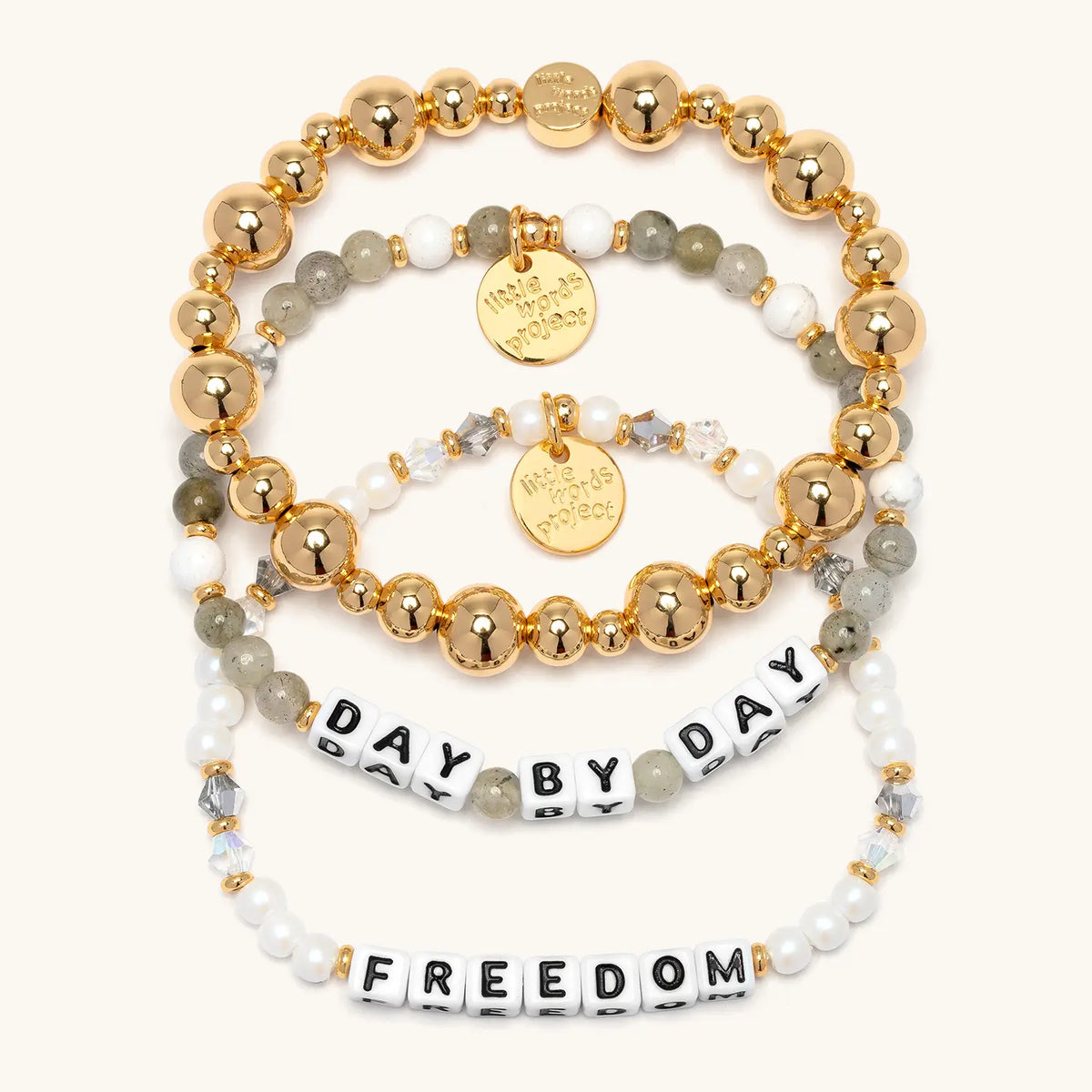 Healing Bracelet Set from the Project HEAL giveback collection, three stacked bracelets: the gold plated Gold Bubbles bracelet base, the Day by Day bracelet, and the Freedom bracelet