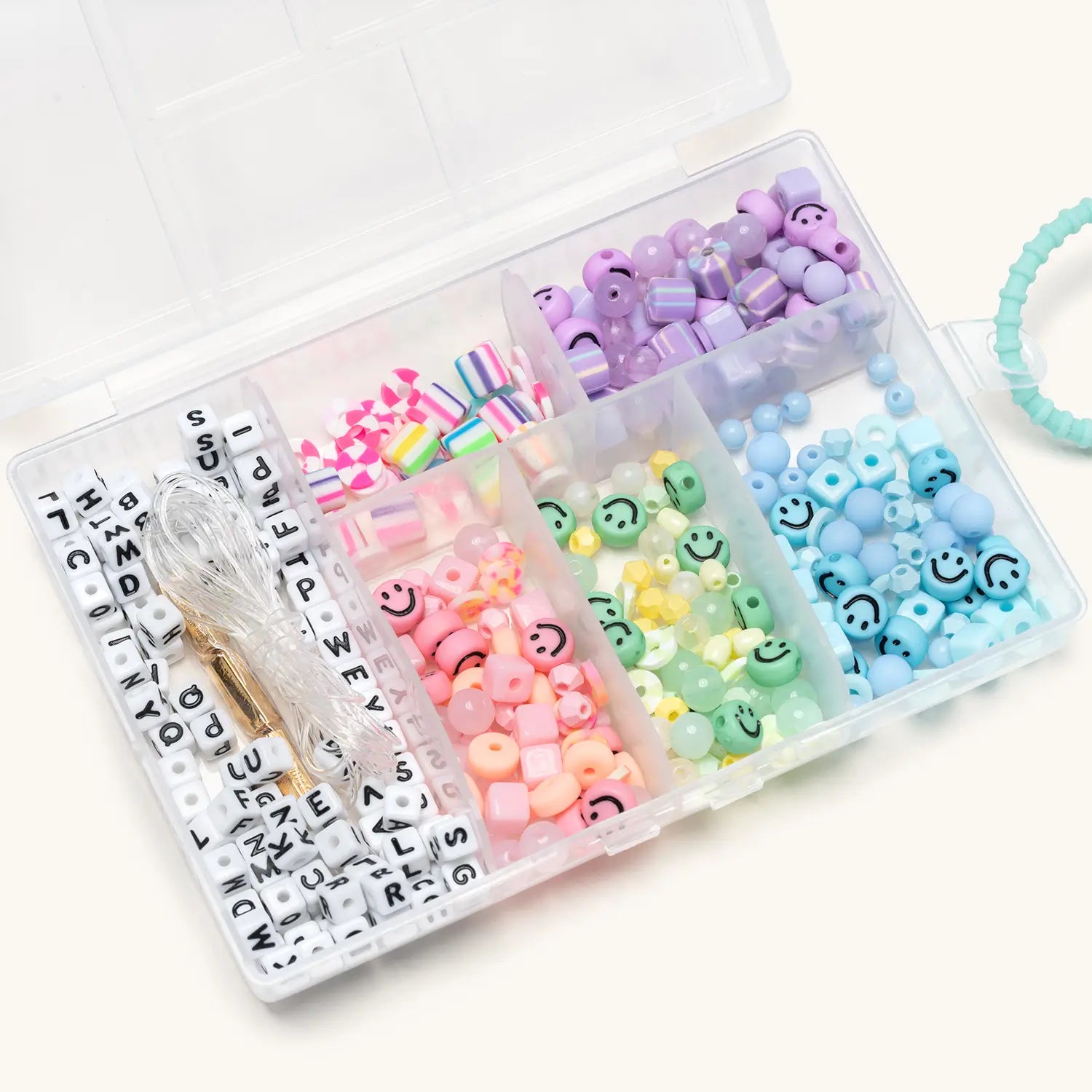 Assorted colorful beads and letter components in a clear plastic case on a white background