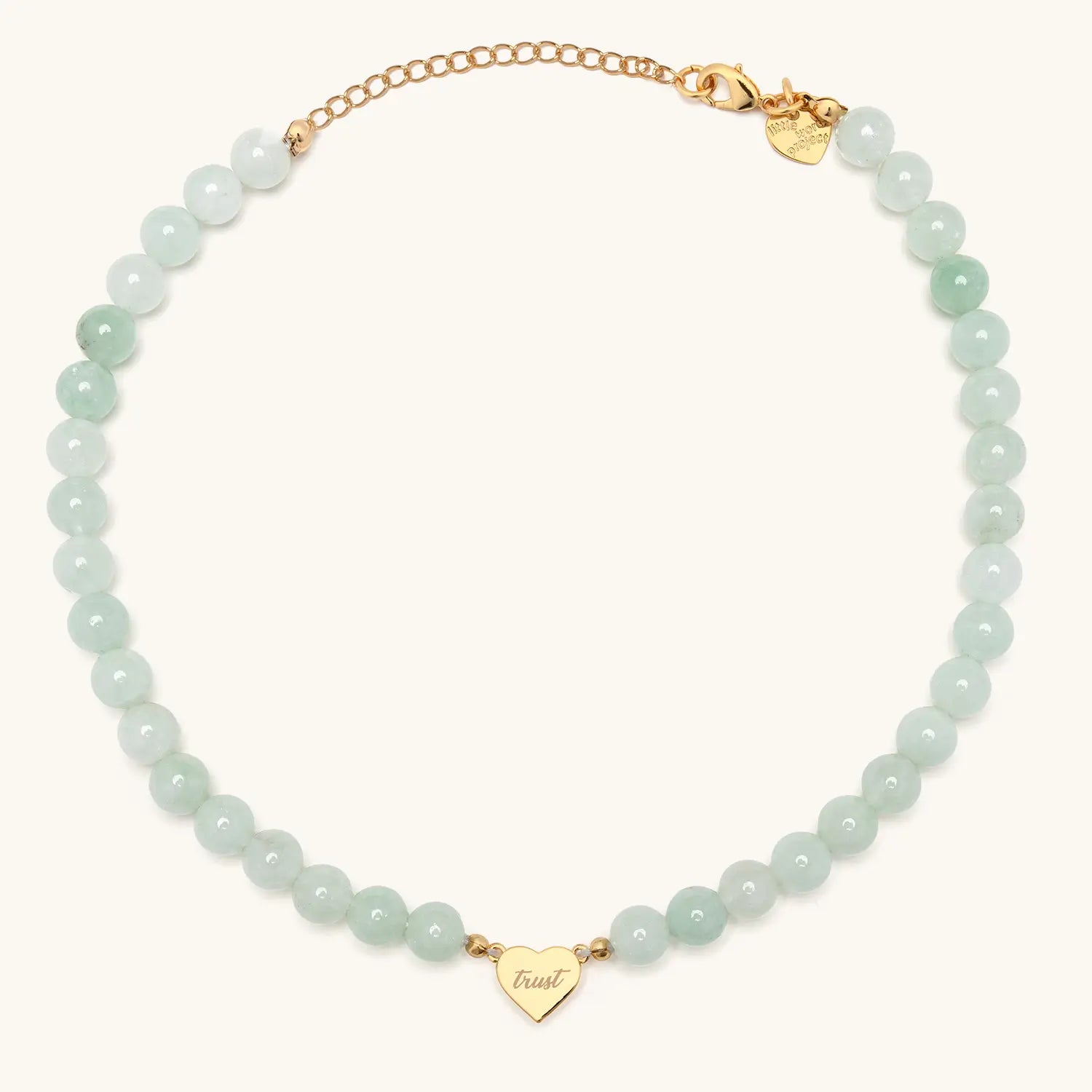 Necklace with white beads and gold accents and a heart shaped pendant against a white background