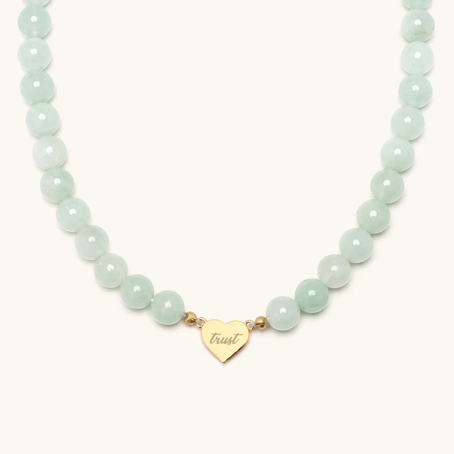 Necklace with white beads and a heart shaped pendant against a white background