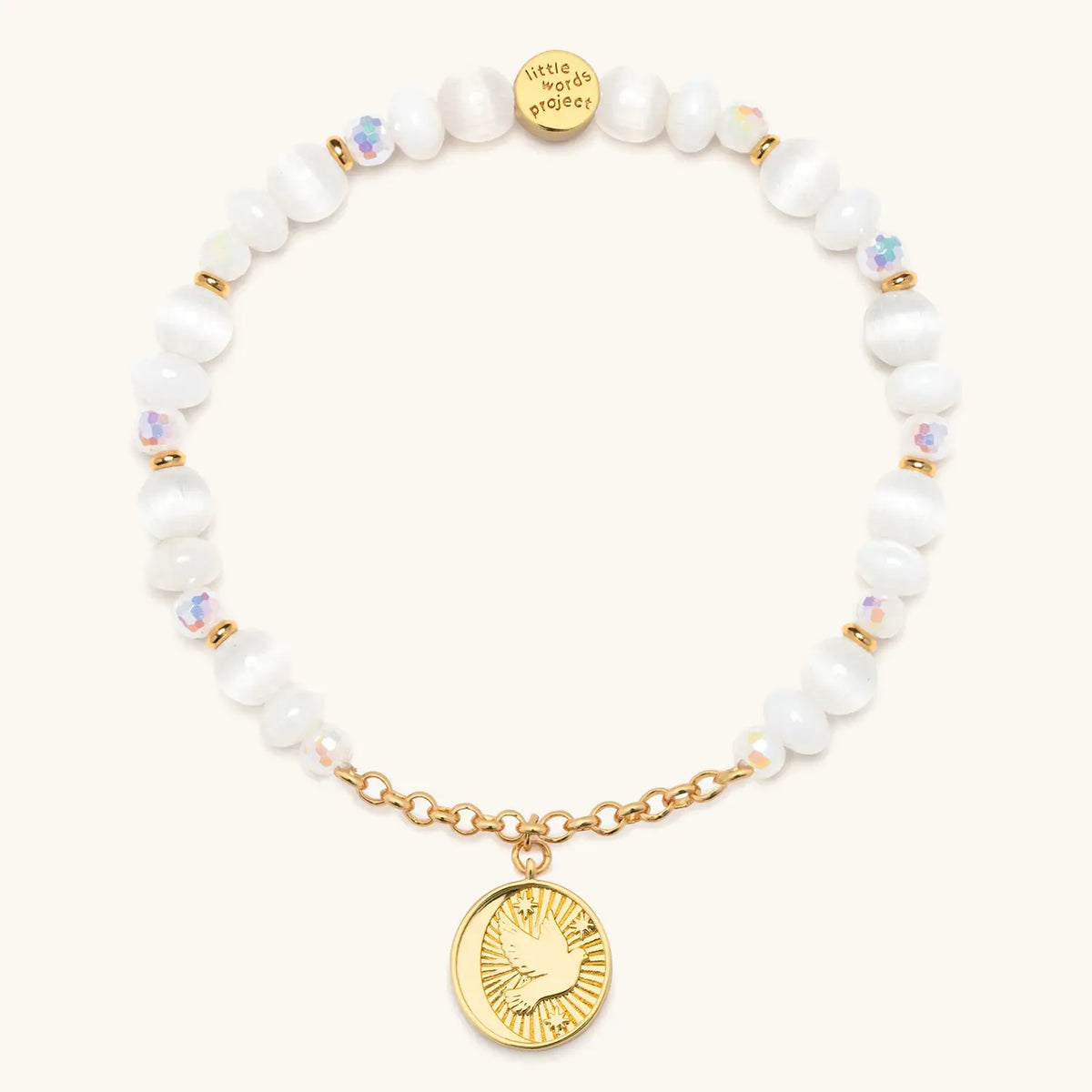 Prioritize Your Peace Charm Bracelet back, white cat eye and iridescent crystal beads with gold chain and a round medallion showing a dove, flat-lay on cream background
