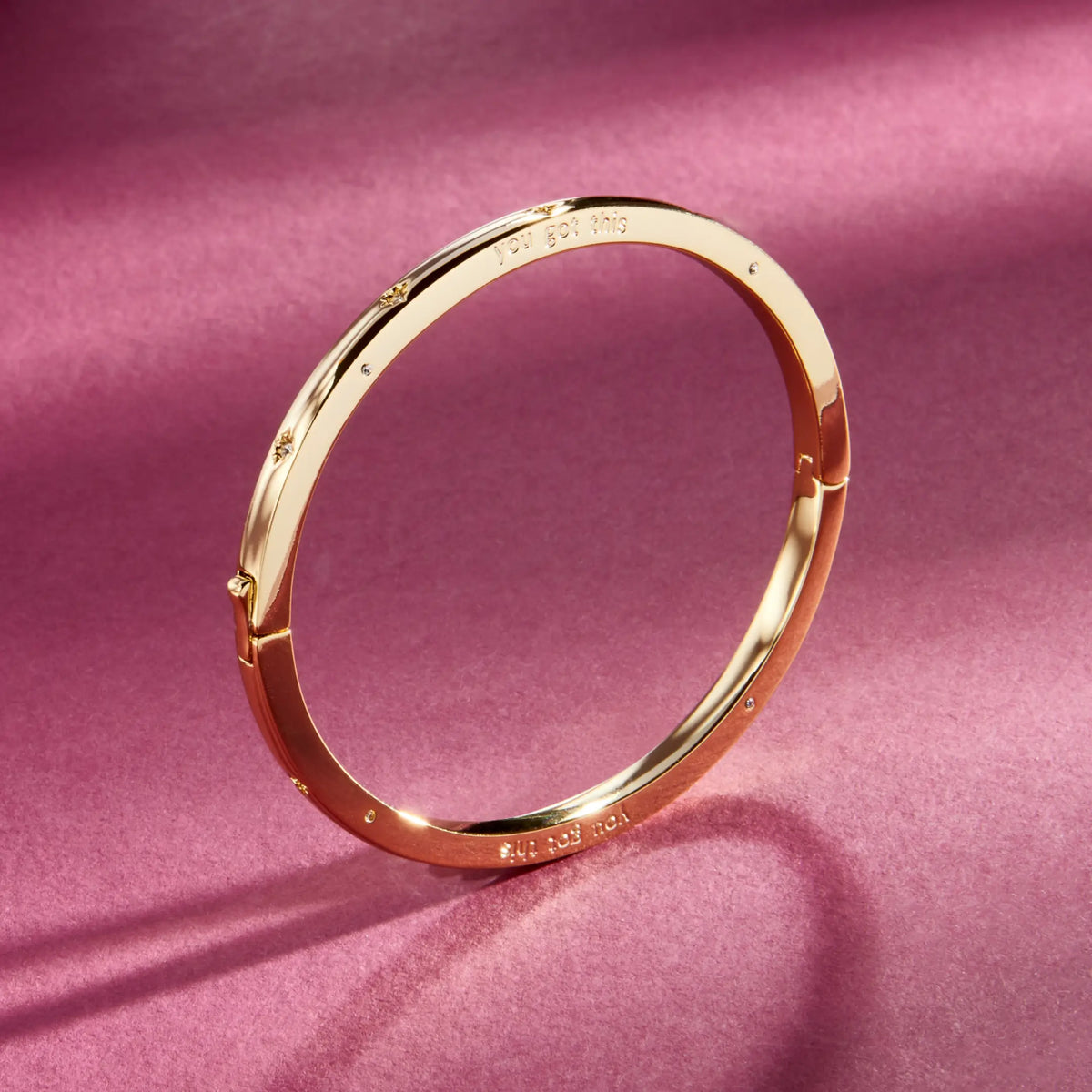 You Got This Bangle, 18k gold-plated bangle with CZ stone details and push button closure, detail on a berry background