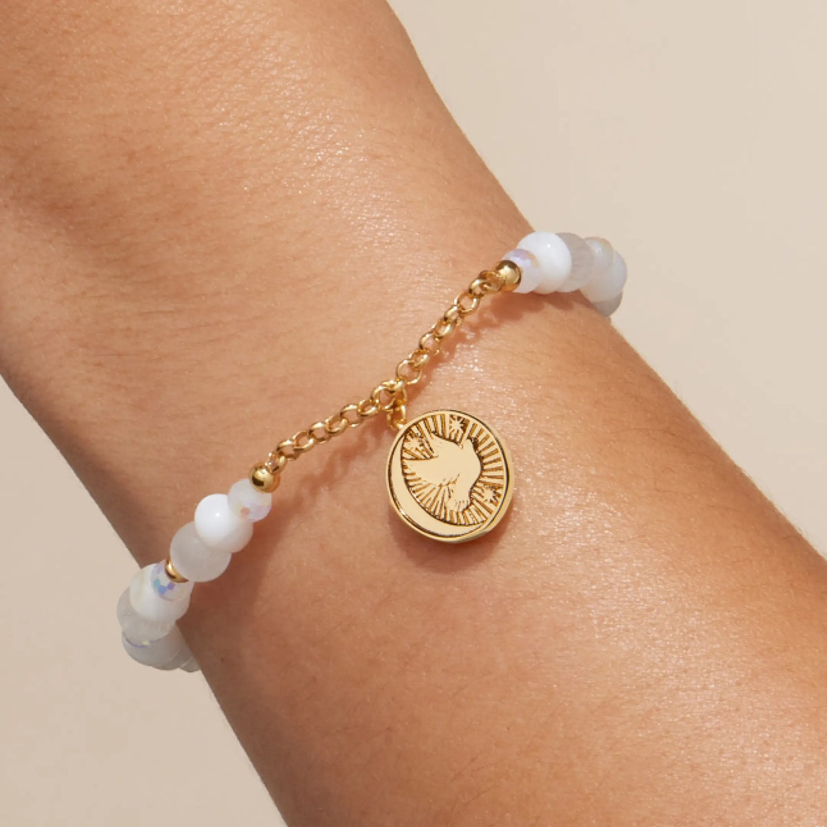 Prioritize Your Peace Charm Bracelet on-model, white cat eye beads with gold chain and the dove side of the round medallion facing out