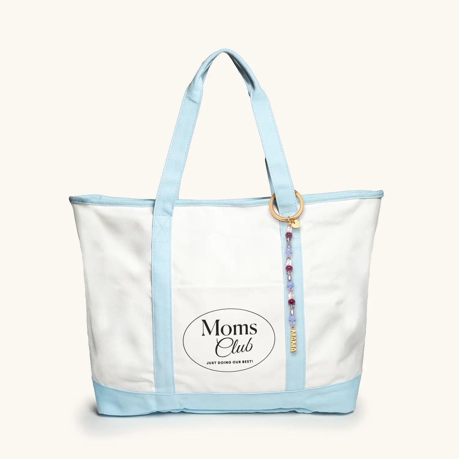 White tote bag with light blue handles and trim, featuring 'Moms Club' logo.