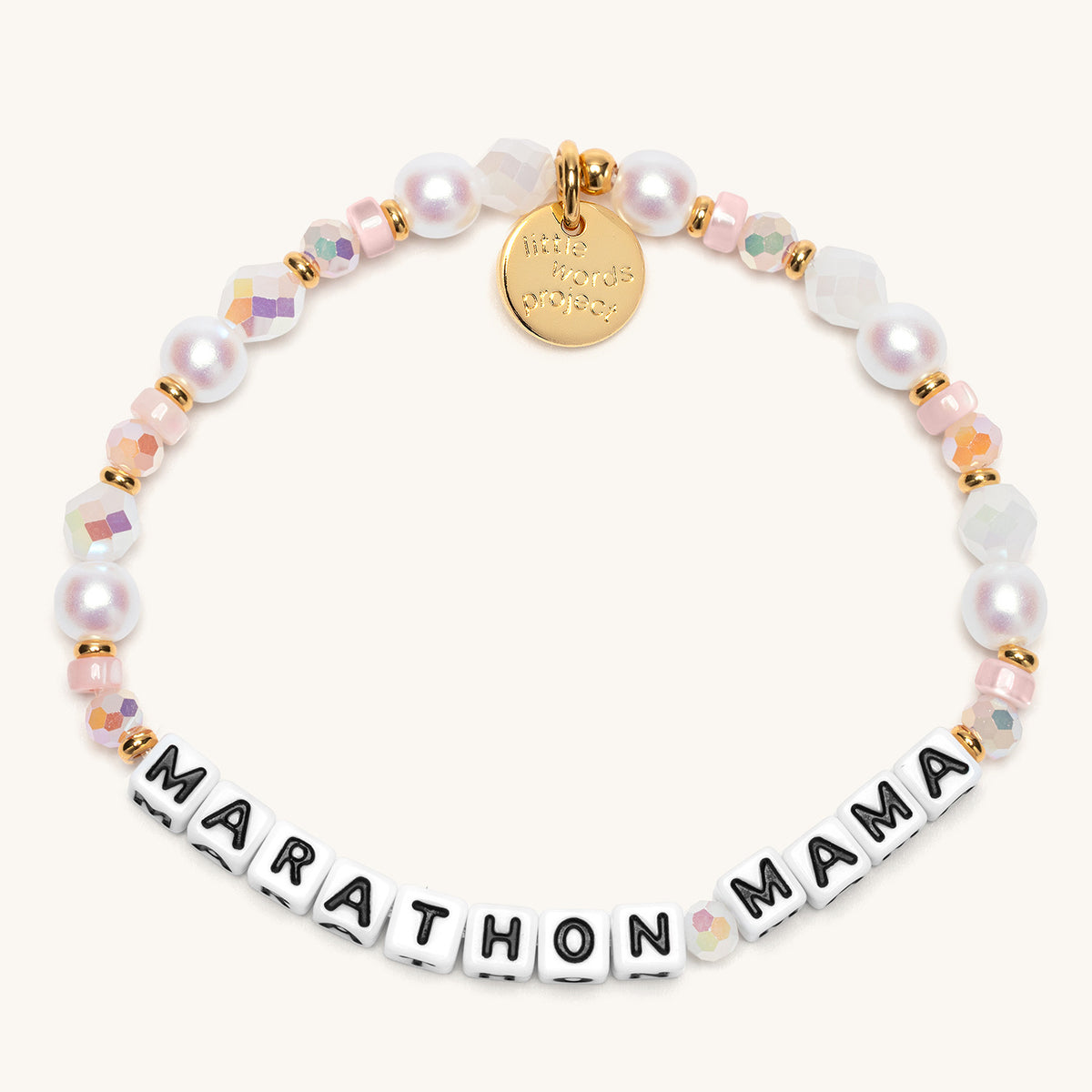 Marathon Mama bracelet in the Studio Lights bead pattern, white letter beads with white faux pearls, iridescent faceted crystals, and blush pink glass beads with gold accents, flat-lay on cream background