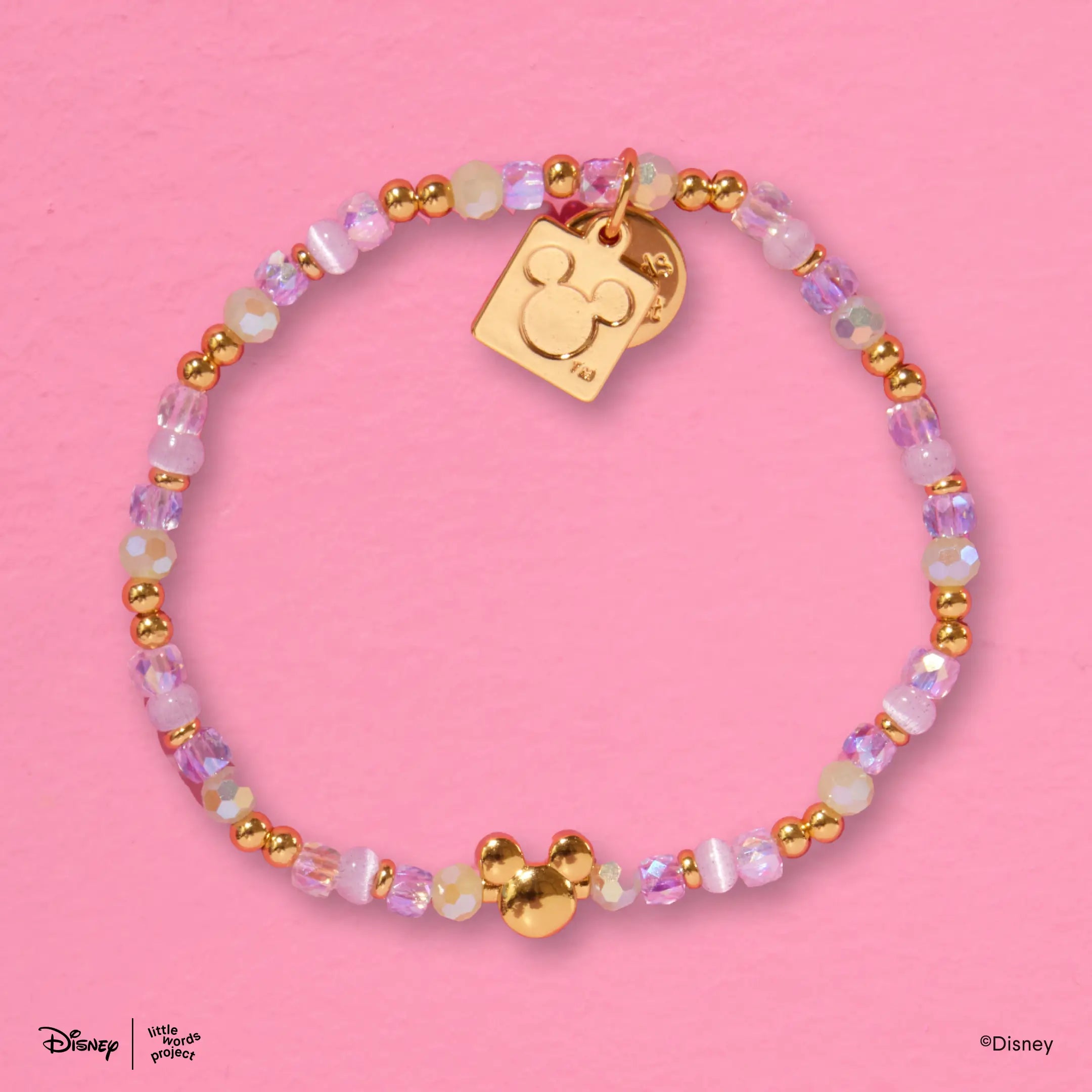 Mickey Mouse Bracelet Base from Disney Mickey and Friends flat lay on pink with pastel beads, a gold Mickey Mouse bead and a gold plated casted Mickey Mouse tag charm