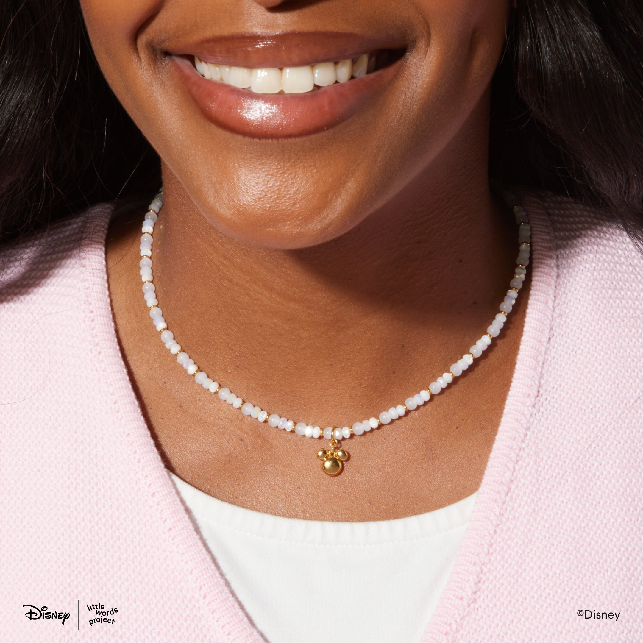 Mickey Mouse Charm Necklace from Disney Mickey and Friends worn on a model in a pink cardigan, white beaded strand with a gold plated Mickey Mouse head pendant