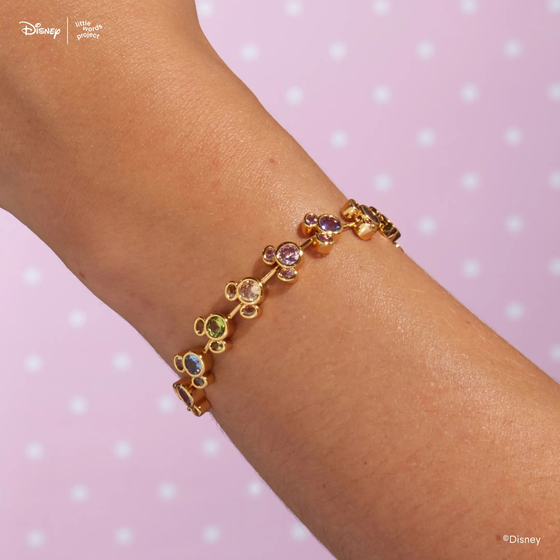 Mickey Mouse Rainbow Bracelet from Disney Mickey and Friends worn on a wrist against a lavender backdrop, gold plated Mickey Mouse links set with multicolor crystals