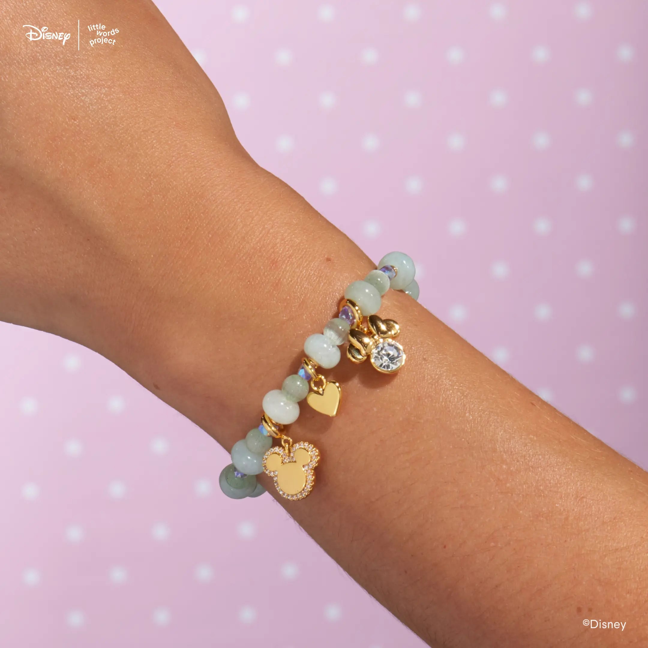 Mickey Mouse and Minnie Mouse Charm Bracelet from Disney Mickey and Friends worn on a wrist, close up of the gold plated heart, Minnie Mouse and crystal charms