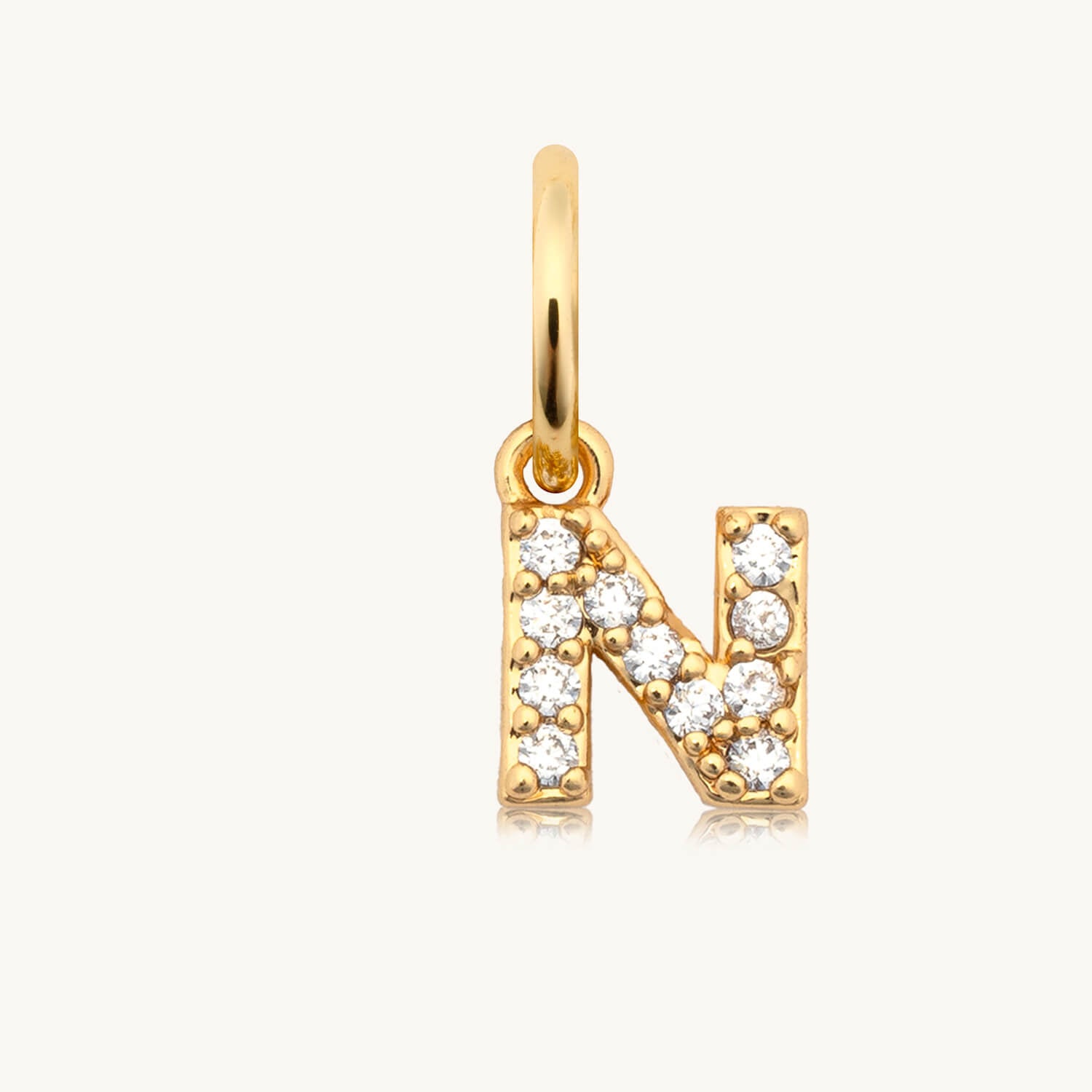 Gold pendant with letter 'N' and clear stones on a white background