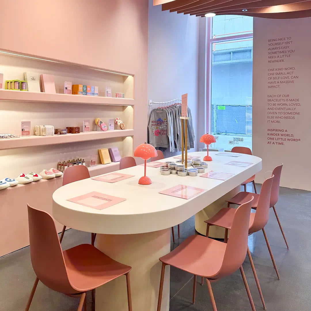 Modern interior with a round white table and pink chairs in a store setting.
