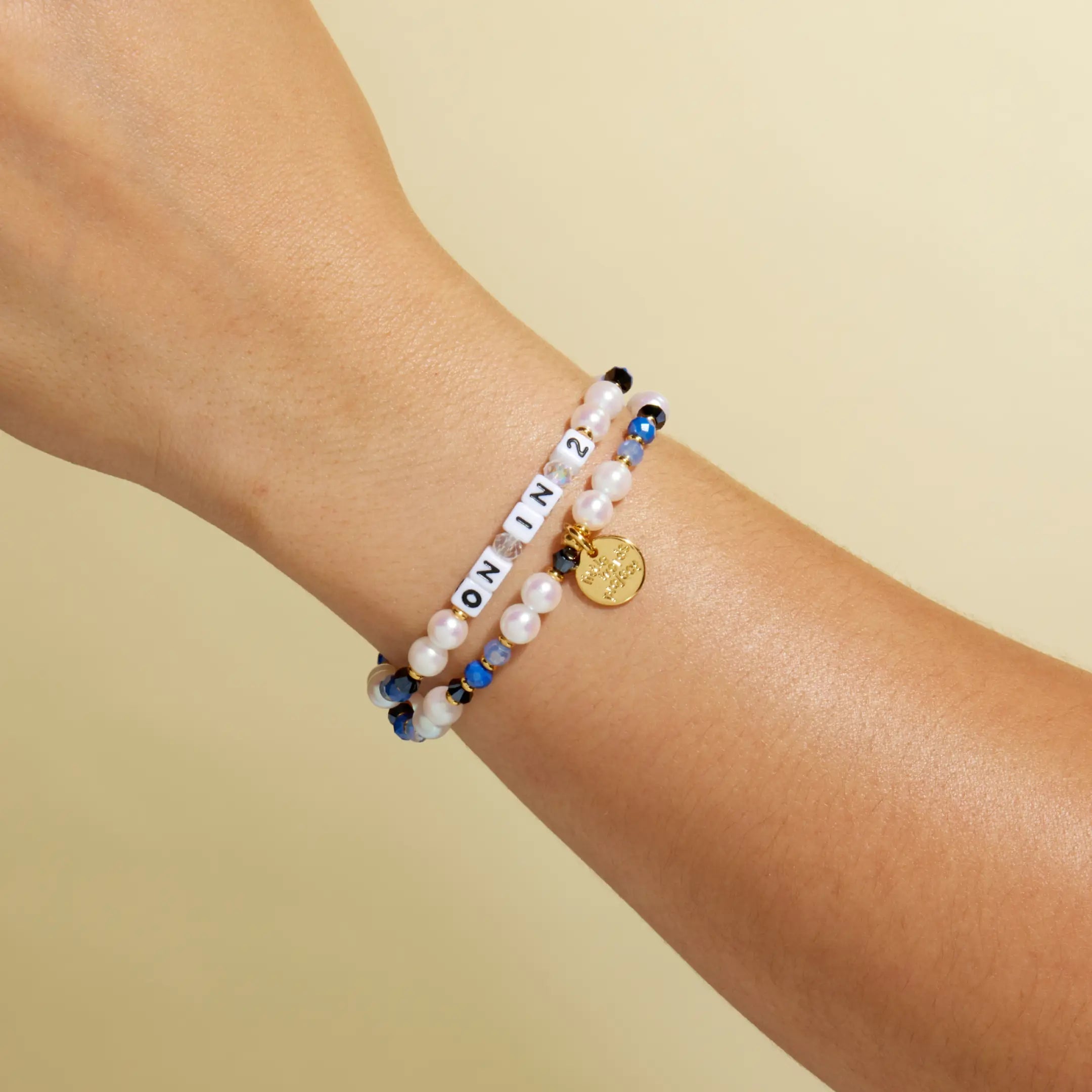On In 2 bracelet stacked with second beaded bracelet, on-model wrist shot against warm neutral background