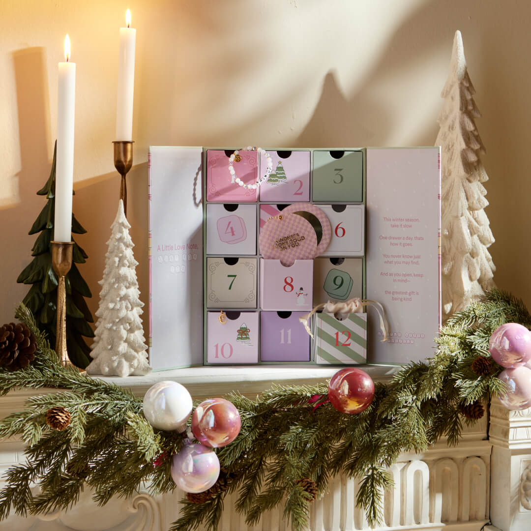 Decorative Advent calendar with Christmas trees and candles on a mantel.